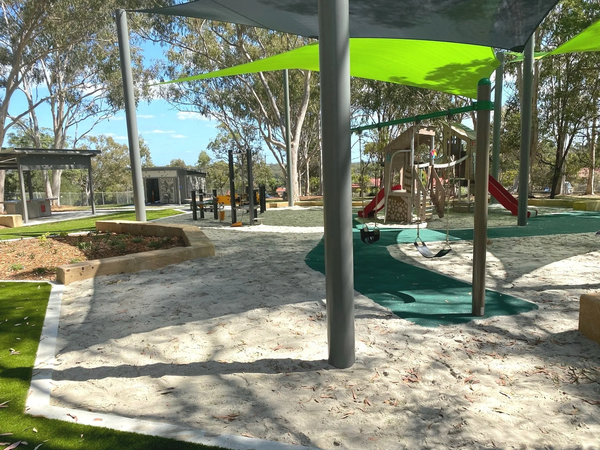 Wide view of Hanover Drive Park showing shaded seating areas and picnic tables for families


