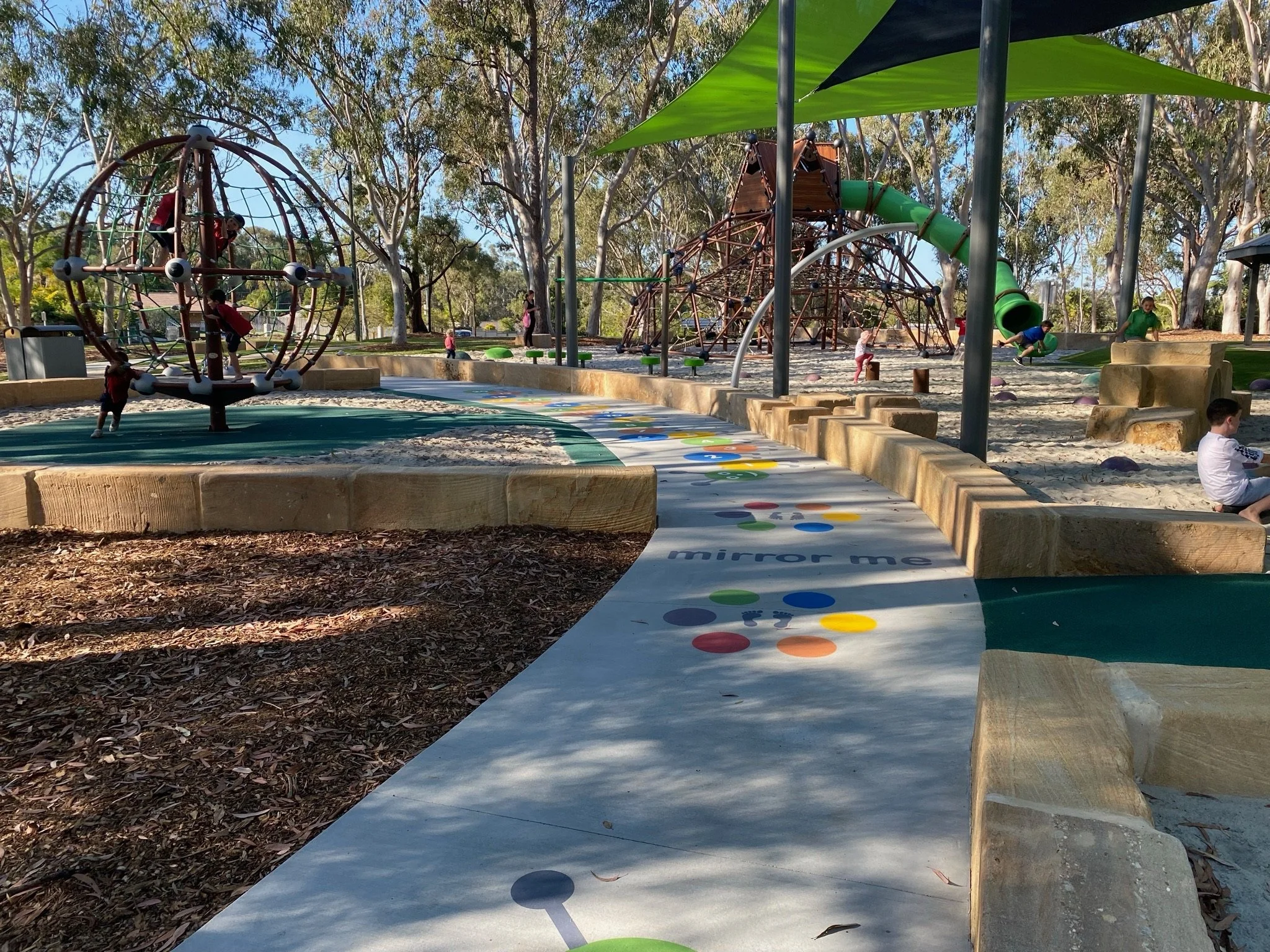 Children engaging in imaginative play on colorful playground structures at Hanover Drive Park

