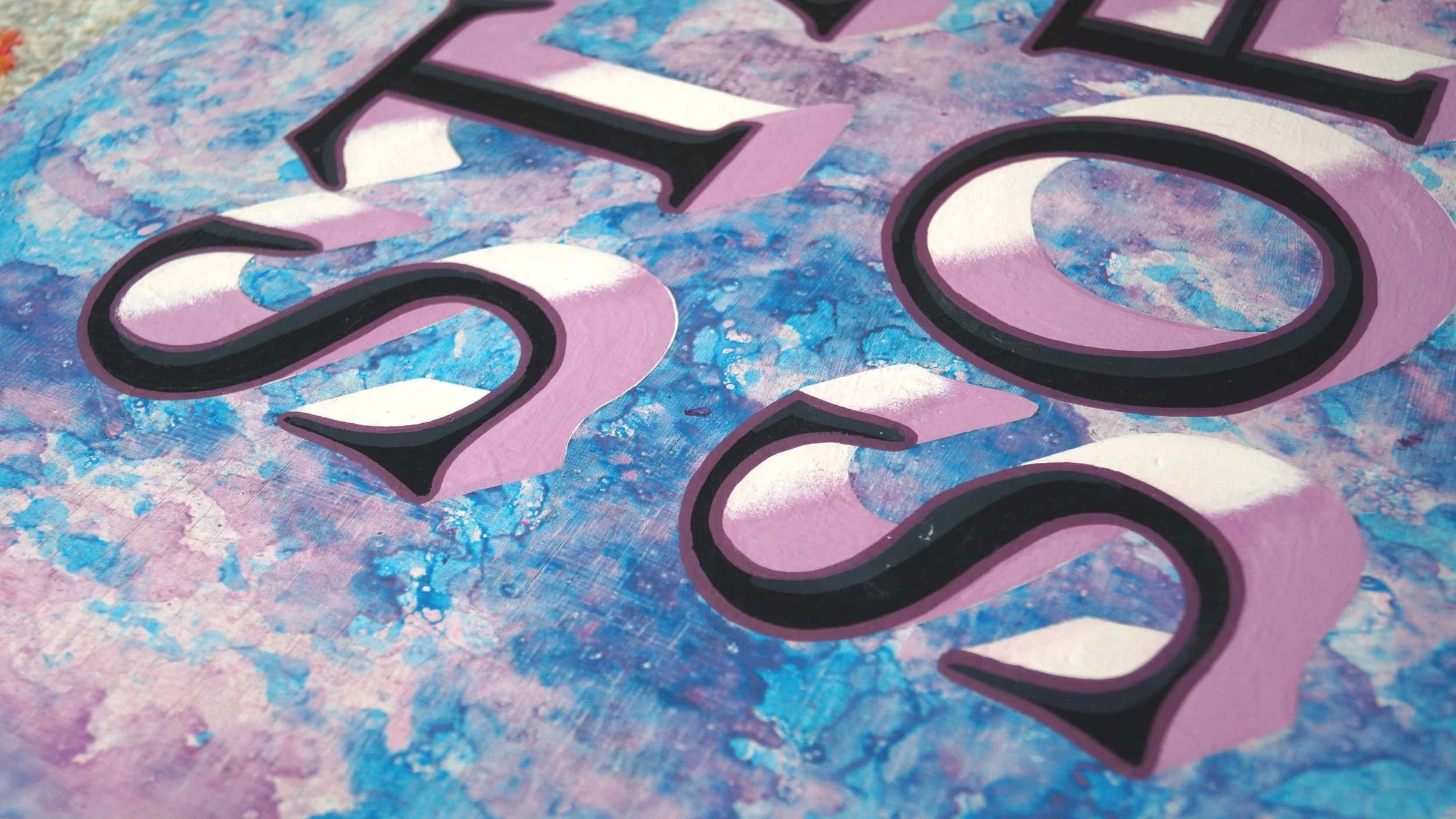 Close-up of a colorful painted background with large three-dimensional numbers '2023' in black, pink, white, and purple.