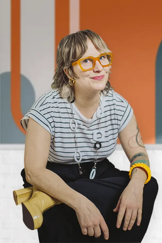 Image of woman half smiling to camera in front of art.