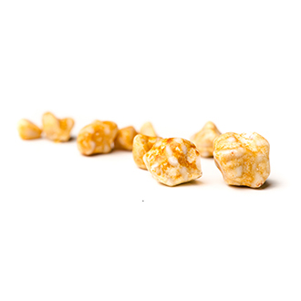 Close-up of caramel popcorn pieces scattered on a white background.