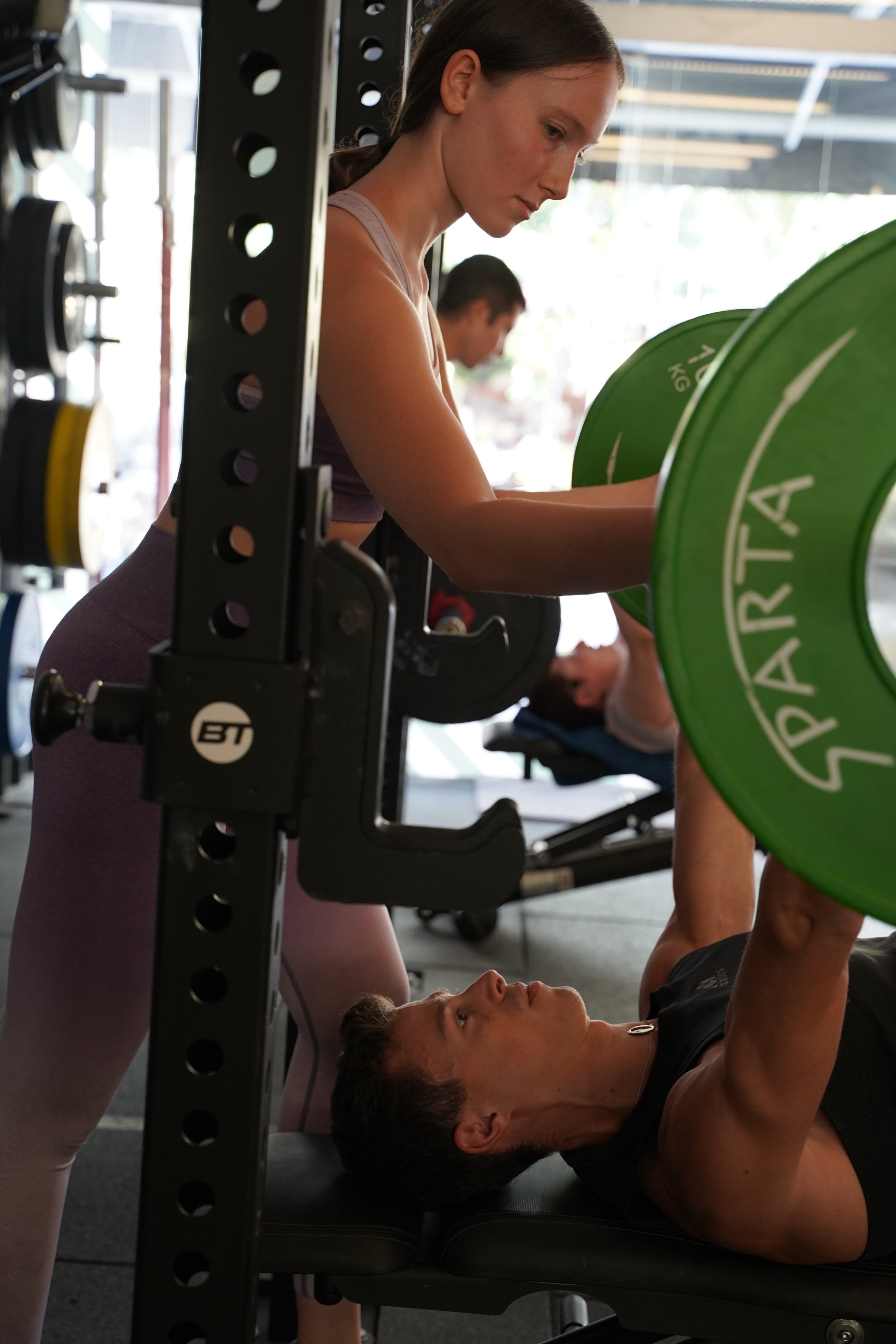 personal trainer spotting a client, a trainee, in chest press exercise.