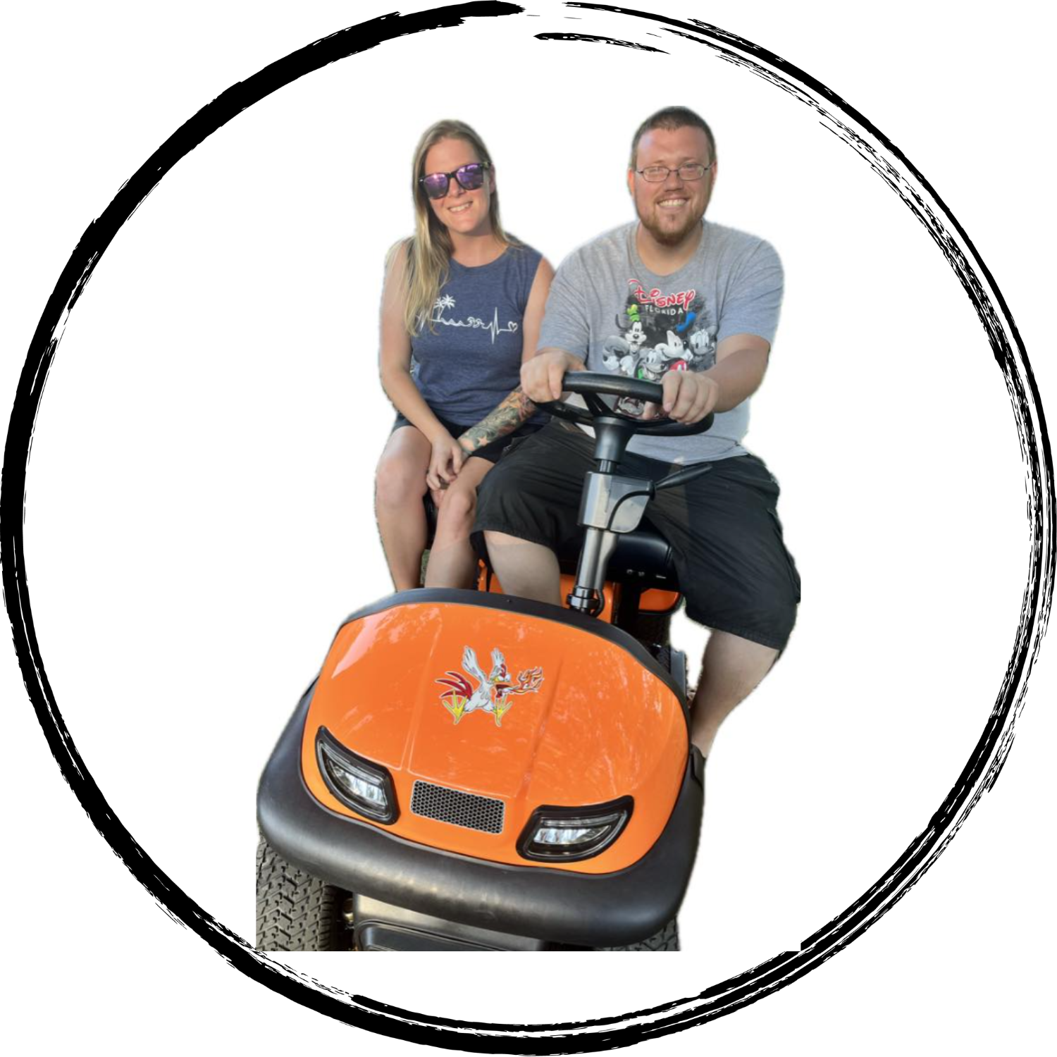 A man and woman riding an orange mobility scooter with a dragon decal, the man is driving and the woman is sitting on the back, both smiling against a white background.