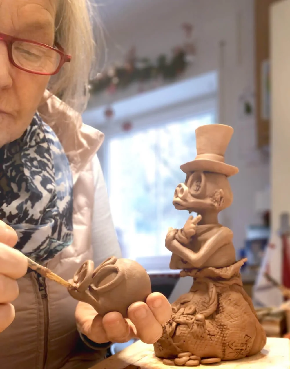 Person formt detailreiche, fantasievolle Tonfigur mit Hut