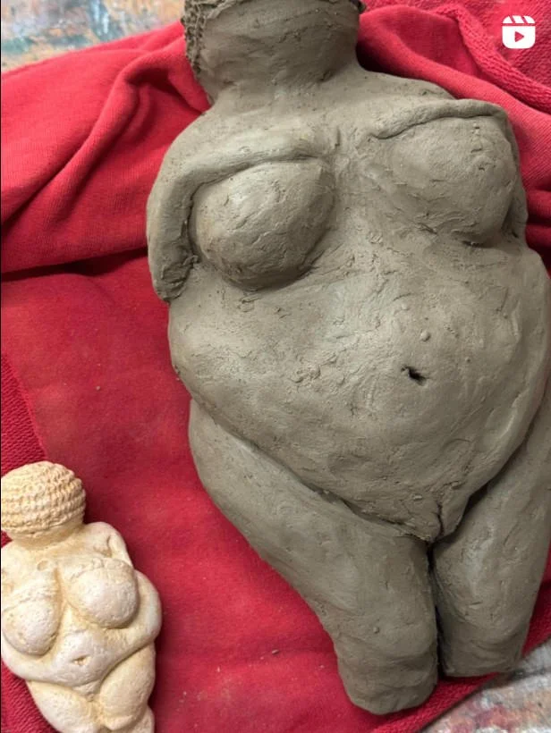 Tonfiguren von Venus-Figurinen auf einem roten Hintergrund; links eine kleine, helle Figur, rechts eine große, dunkle.
