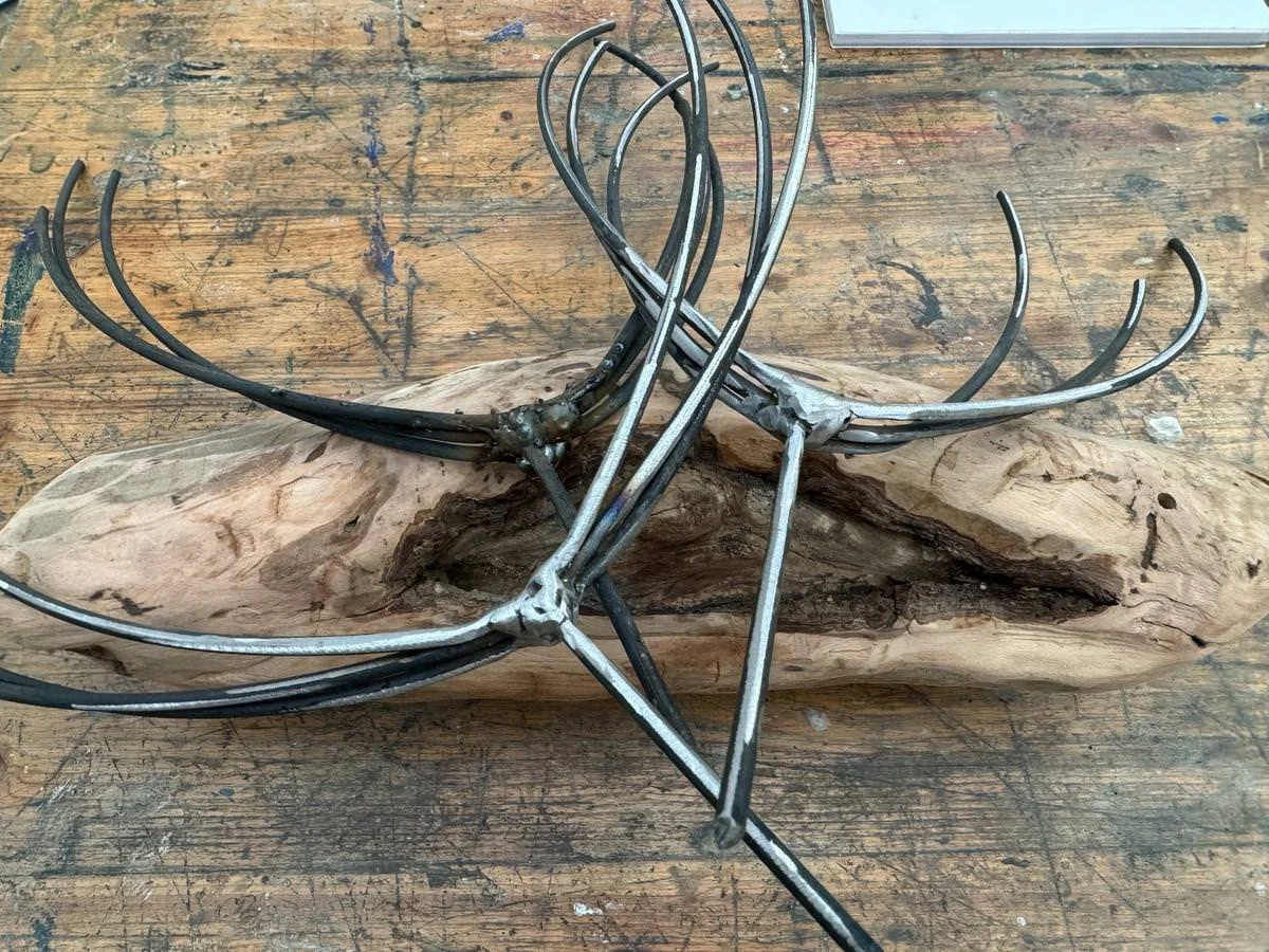 Metallskulptur mit Holz auf einem Arbeitstisch.