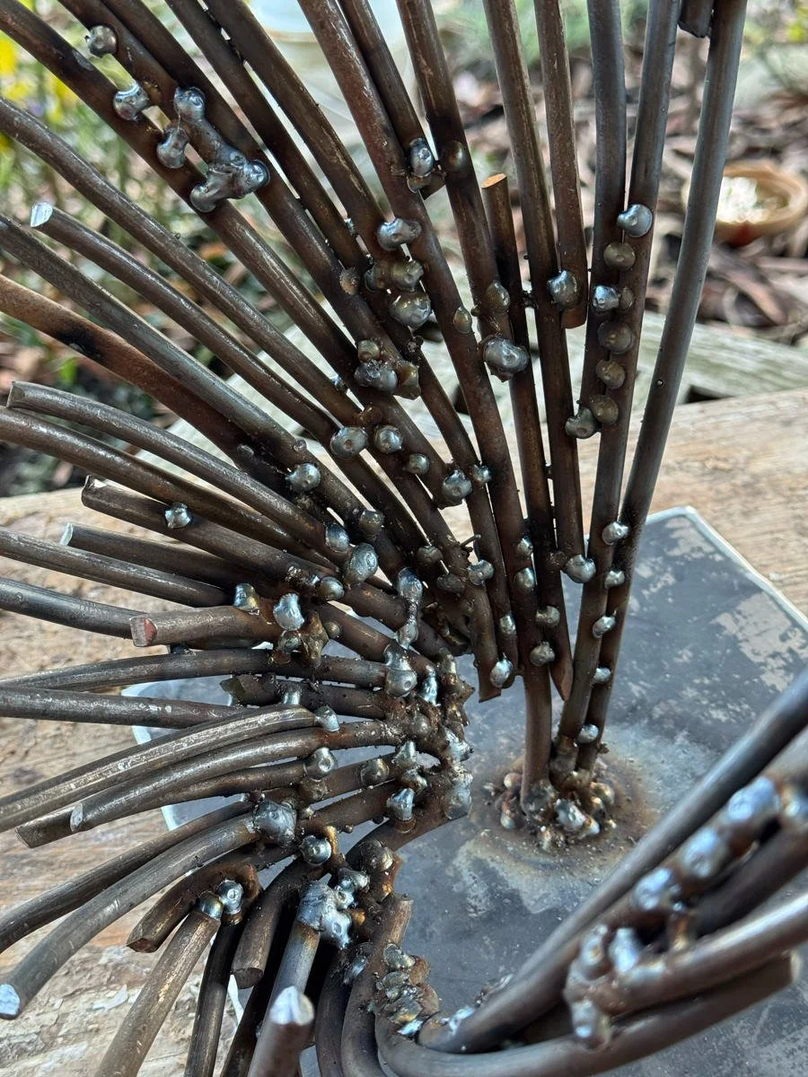 Nahaufnahme einer metallischen Skulptur mit gebogenen und verschweißten Metallstäben.