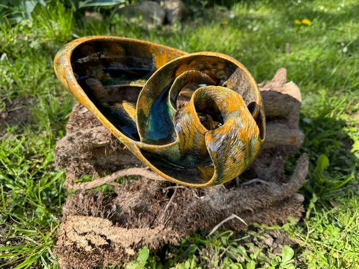 Tonskulptur auf einem Baumstamm im Garten