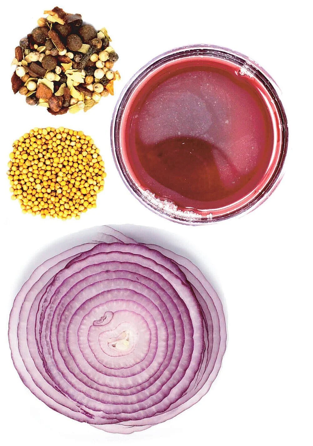 A glass of red liquid, a halved red onion, mustard seeds, and mixed pickling spices on a white background.