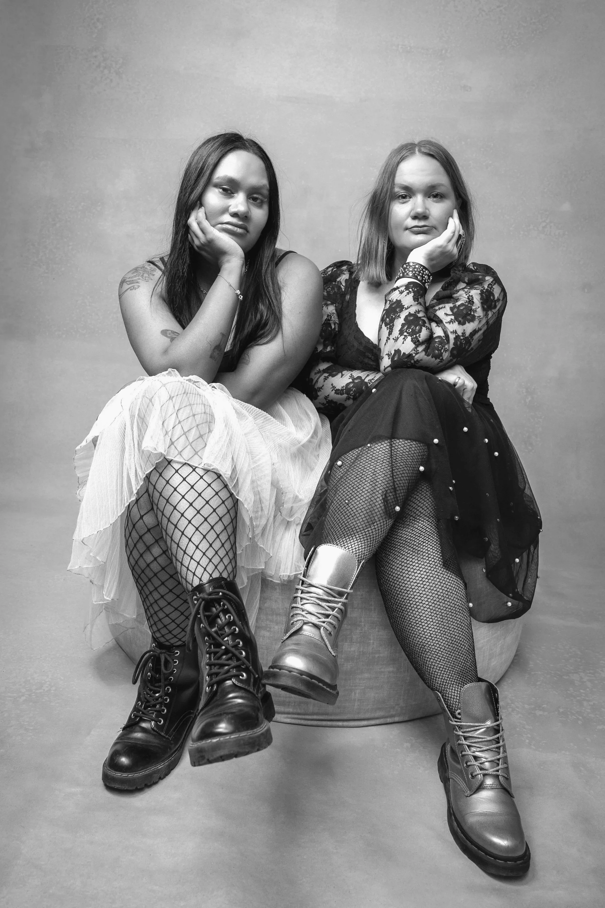 Kuvassa on kaksi naista istumassa tuoleilla. He ovat valokuvastudiolla podcastin promokuvauksessa. Naisilla on tyllimekot päällä ja maiharit jaloissaan. Valokuva on mustavalkoinen. Valokuvaaja Iina Ikävalko, Helsinki. 