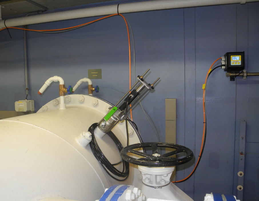 Gesloten witte tanks met pijpen, meters en bedieningspanelen in een technische ruimte.