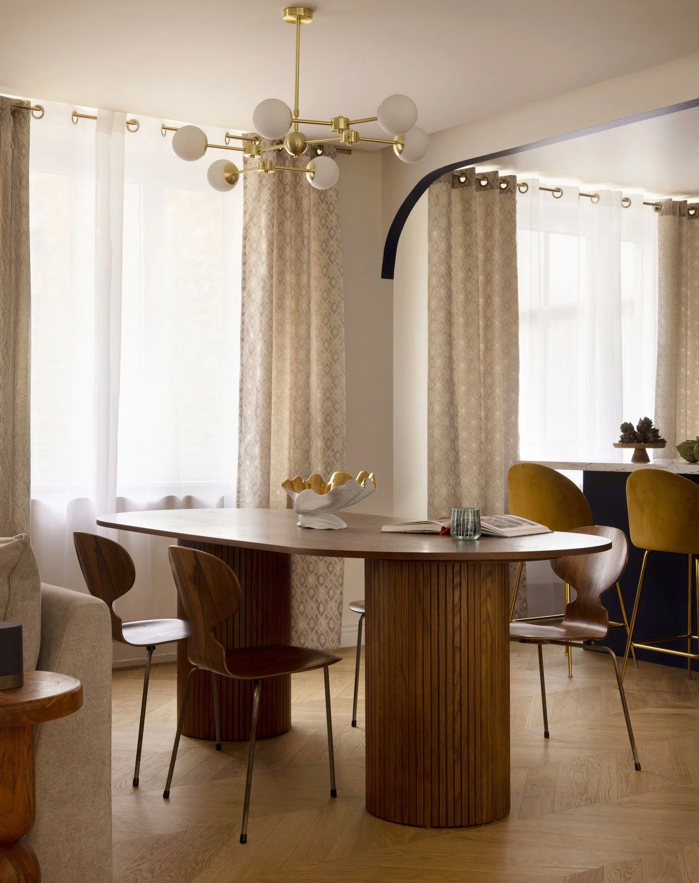 | A transitional Parisian apartment | The dining room opens harmoniously onto a streamlined kitchen, creating a bright, convivial space. The combination of noble materials and soft hues reflects our vision of an interior combining modernity and timel