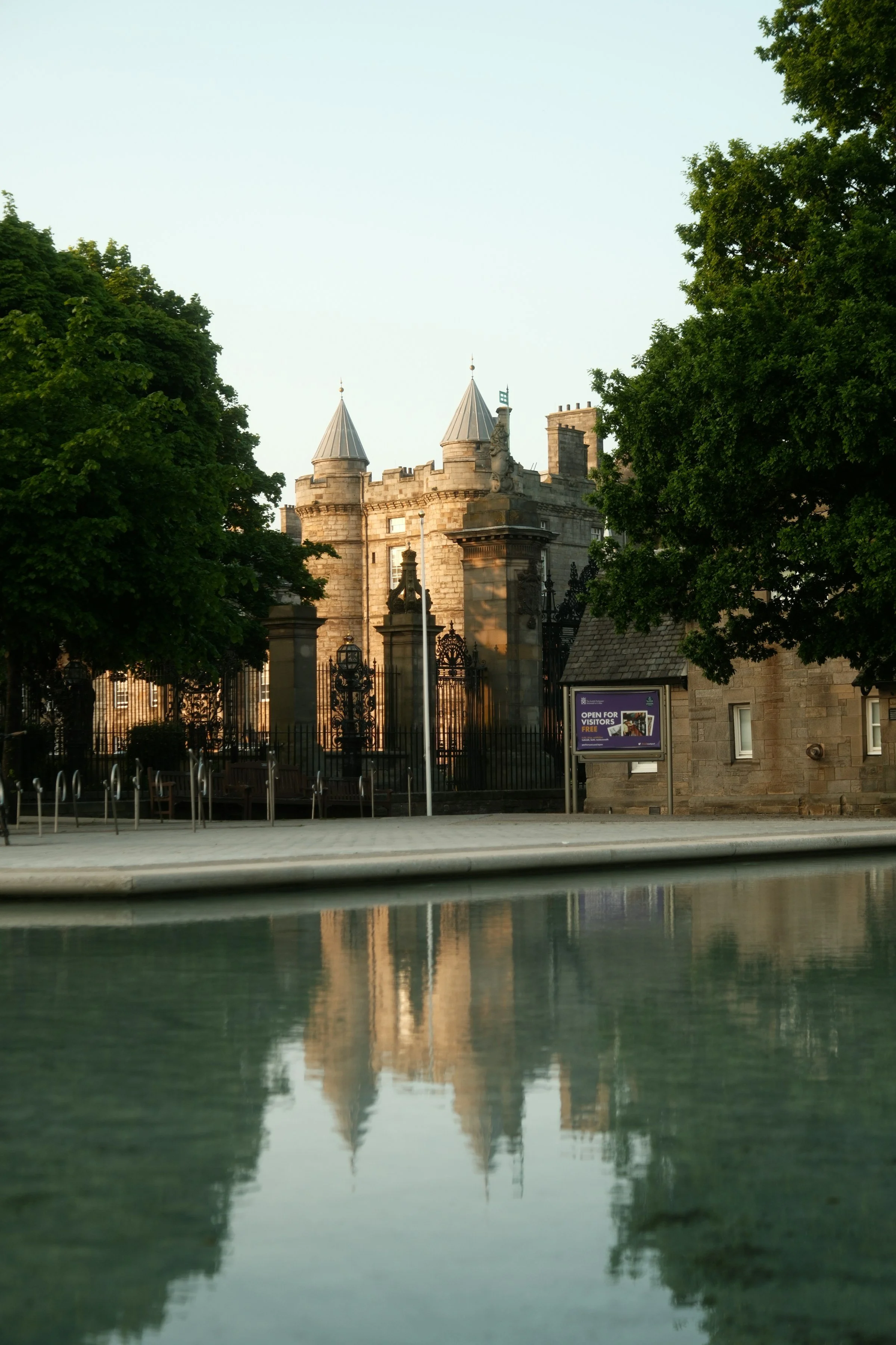 Historic gatehouse of the Palace of Holyroodhouse in Edinburgh, reflected in the water outside the palace grounds.