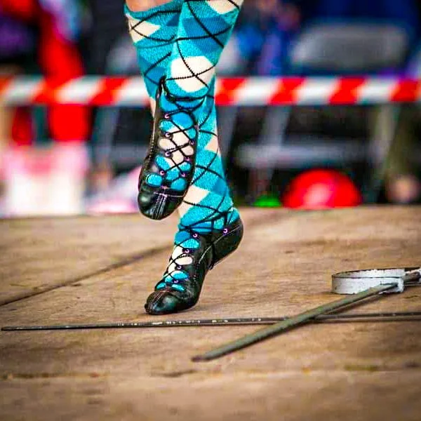 Close-up of a Highland dancer’s feet in ghillie shoes and traditional tartan socks during a competition at the Luss Highland Gathering
