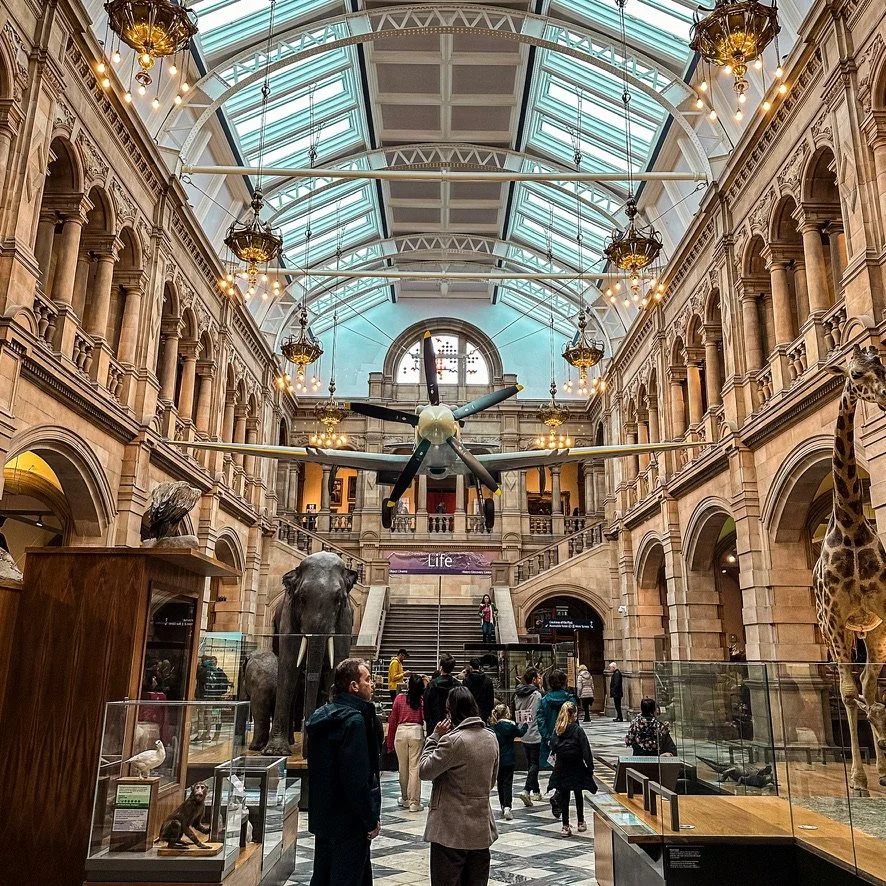 Interior of a museum with exhibits displayed and a spitfire hanging from the ceiling