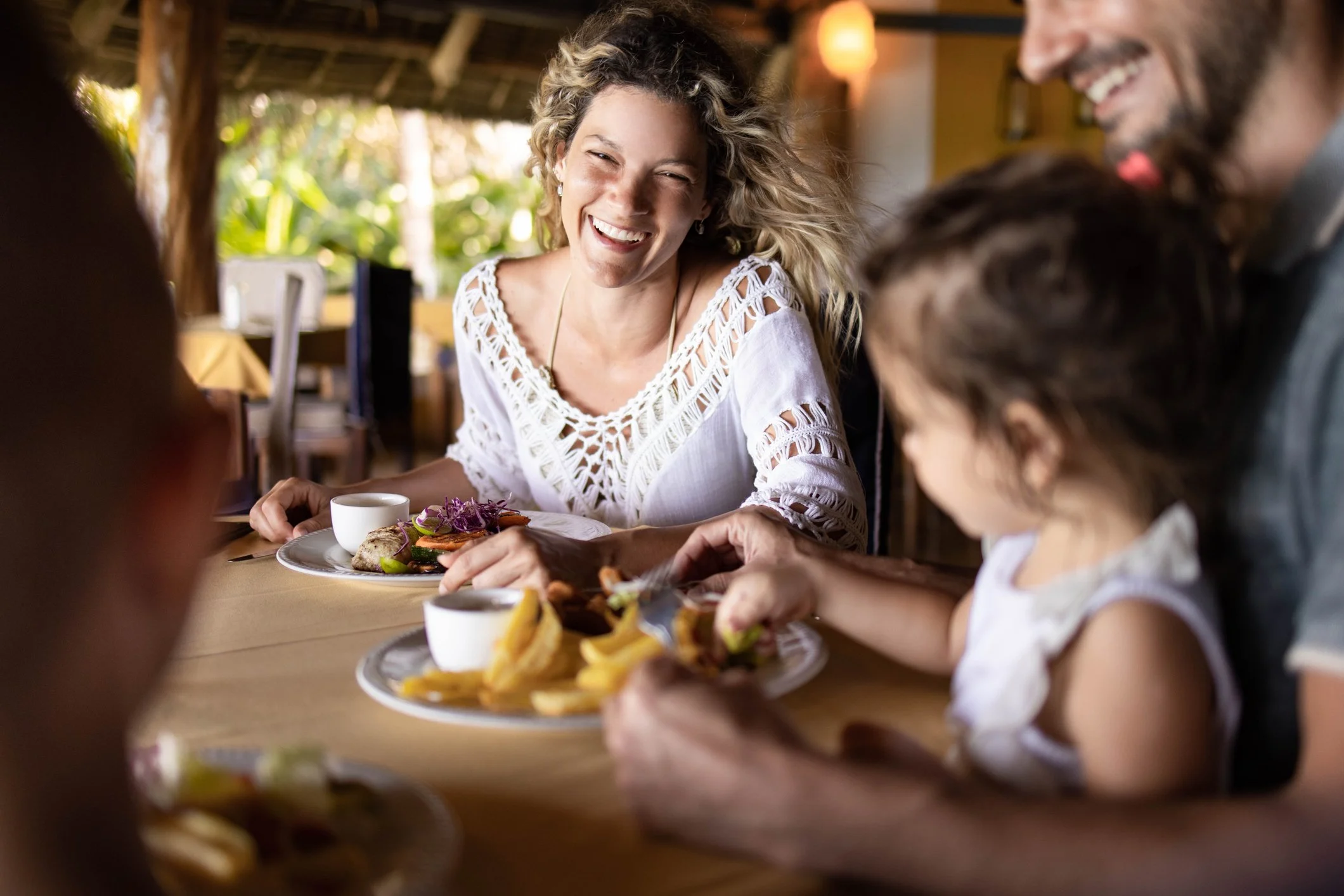 Family smiling and dining at a restaurant, enjoying a meal together.