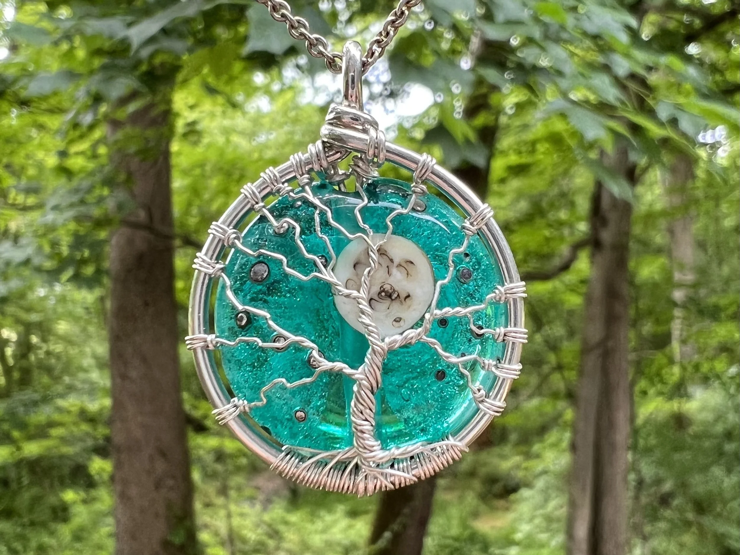 Artistic pendant with wire tree design on turquoise background
