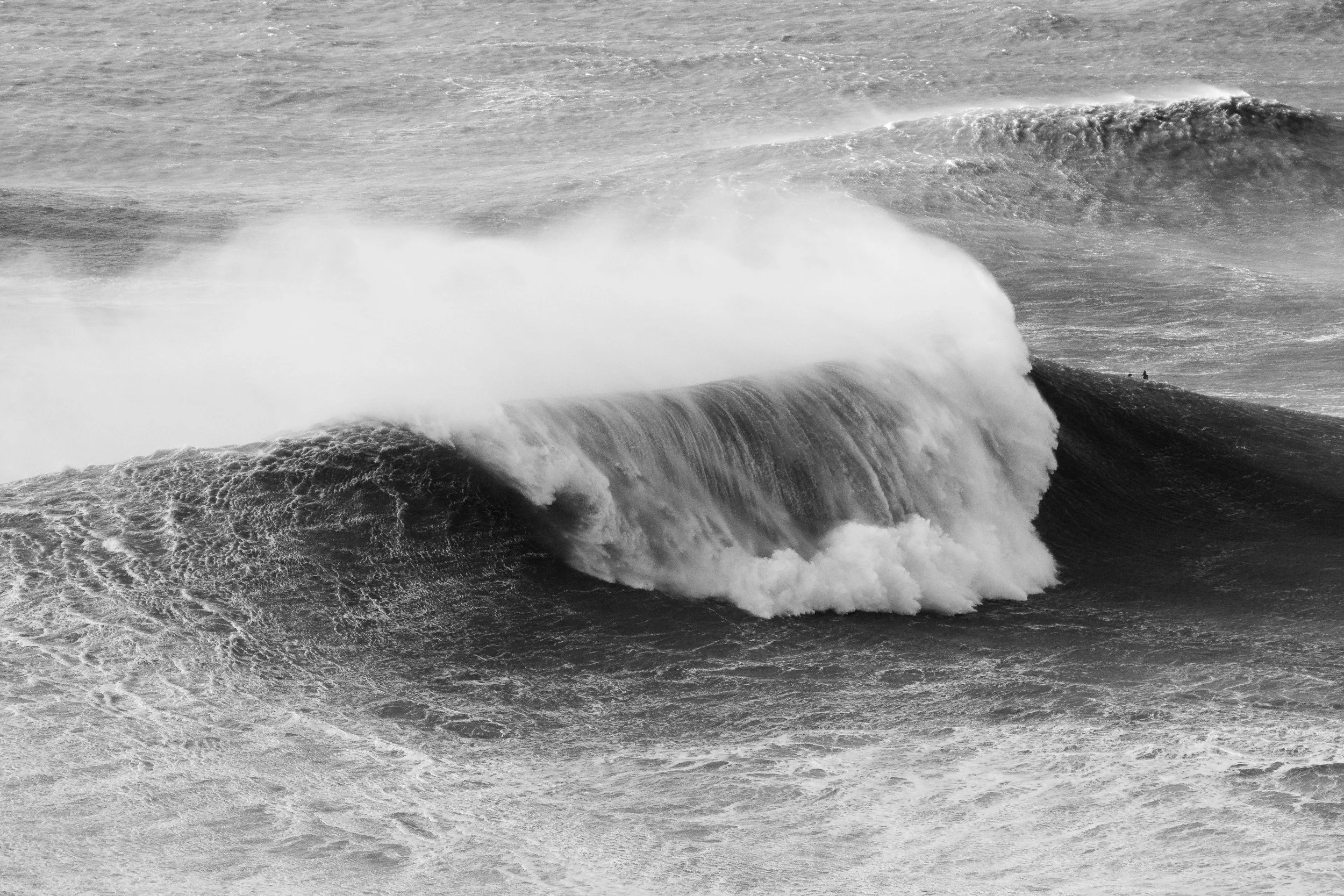 Black and white photo of ocean waves crashing against rocks.