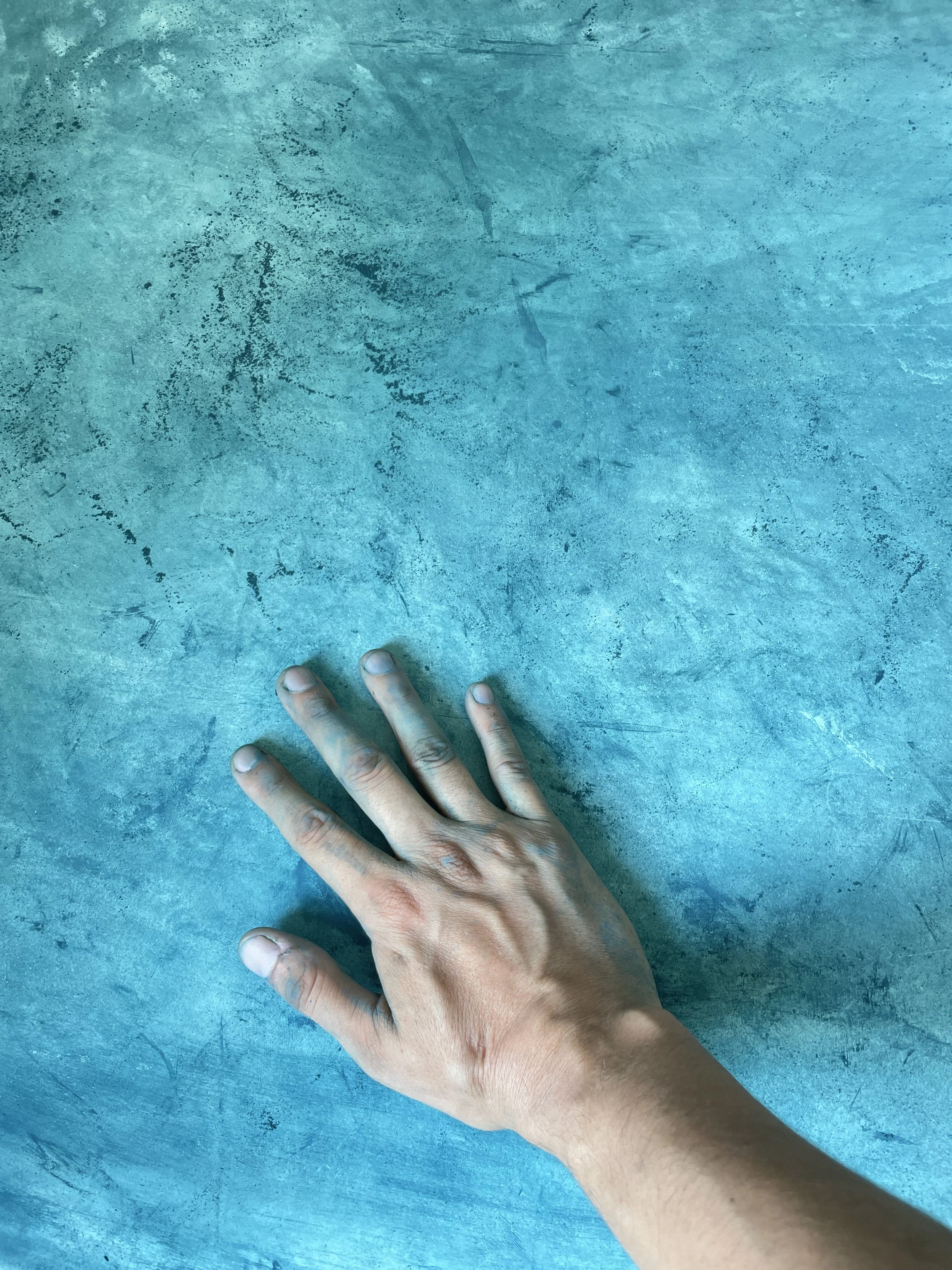 Carlos from Hypha Inc hand with light skin rests on a textured teal surface Verde Maya DYE . Hypha Inc Marketing Agency and Creative Studio Lab, Tulum.