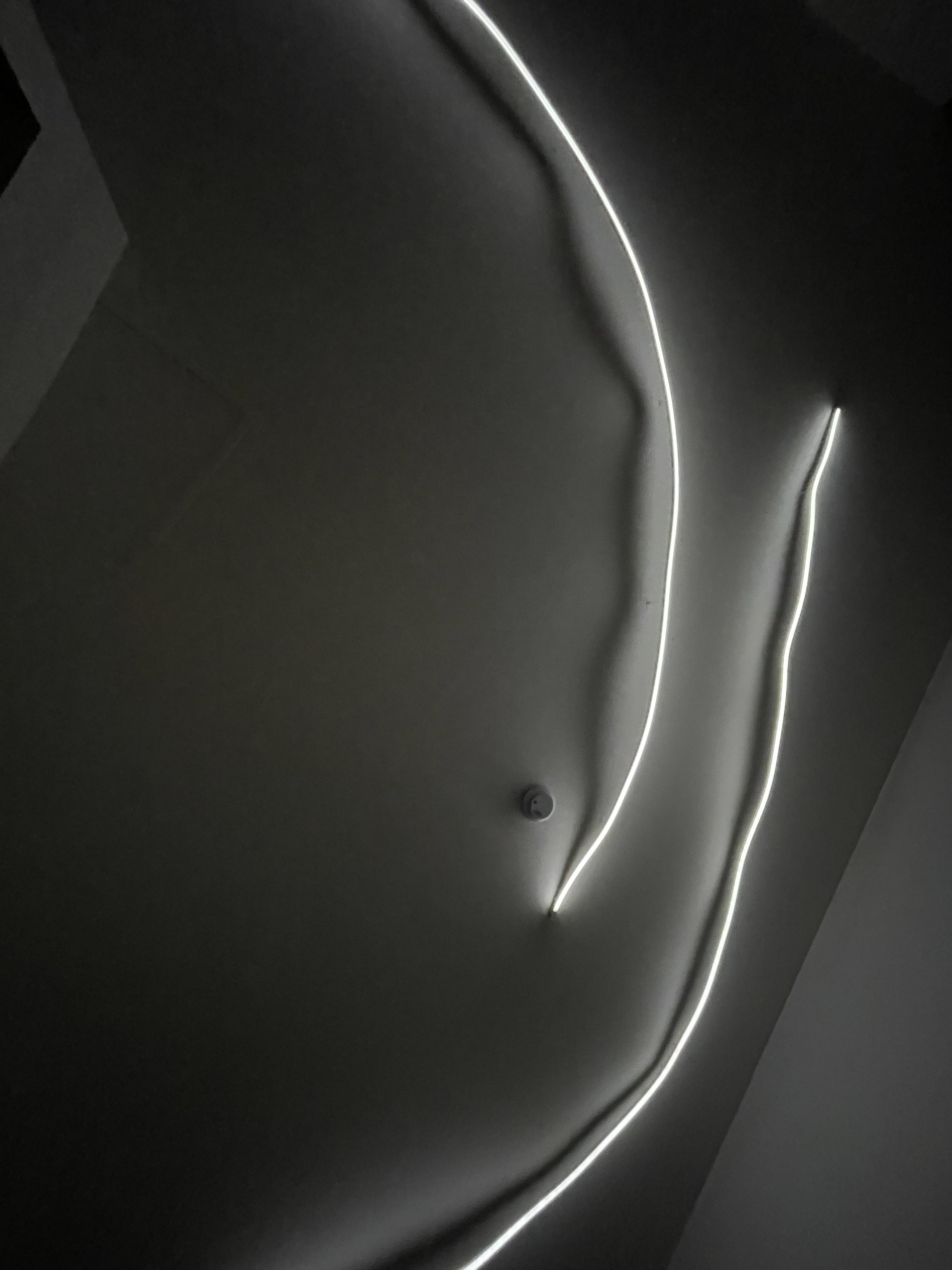  Close-up of a modern ceiling with wavy LED light strips on a dark ceiling. Hypha Inc Marketing Agency and Creative Studio Lab, Tulum.
