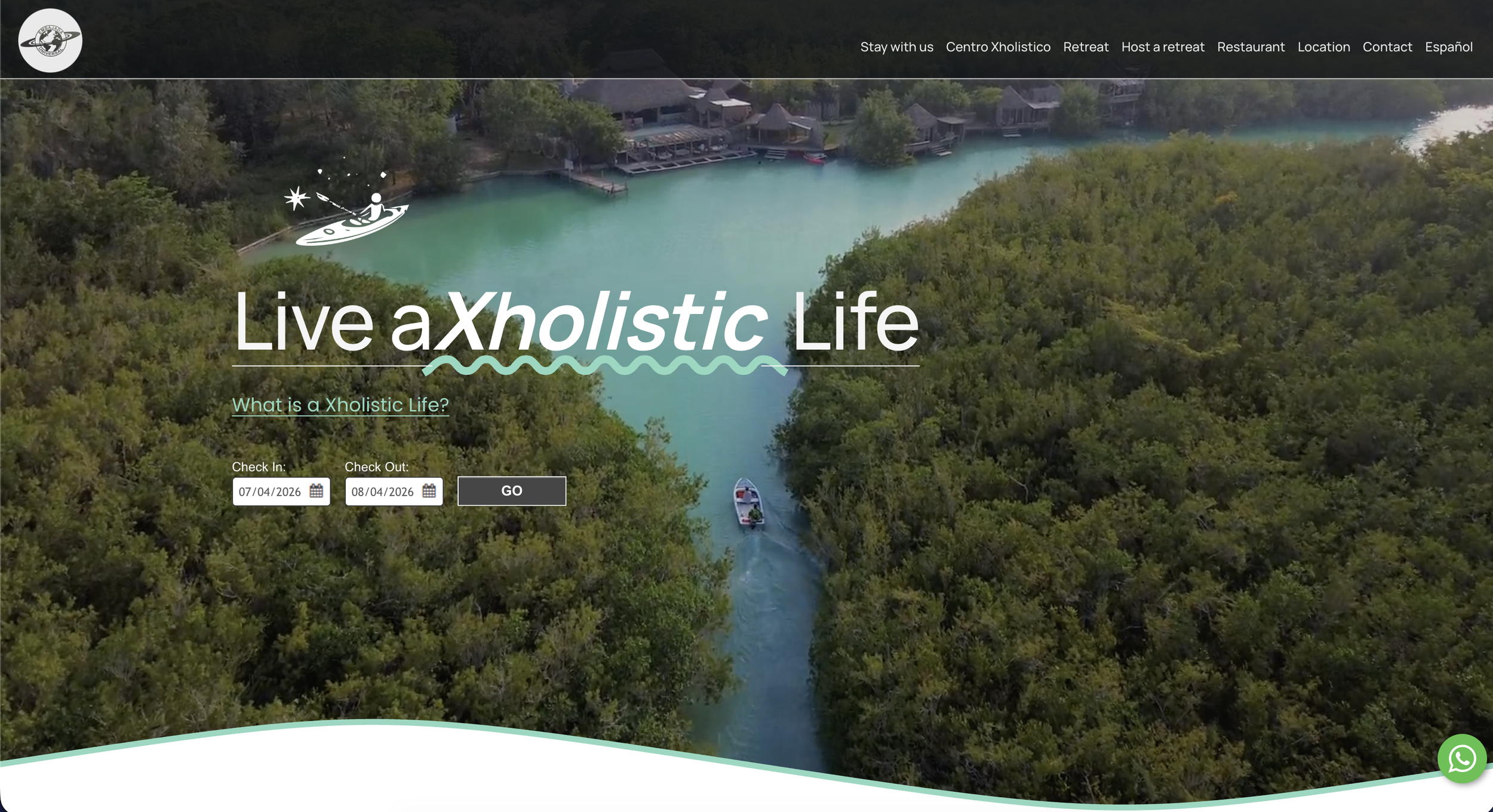 Aerial view of a lush forest surrounding a turquoise lake with a boat and kayaker, with a resort and trees along the shoreline.