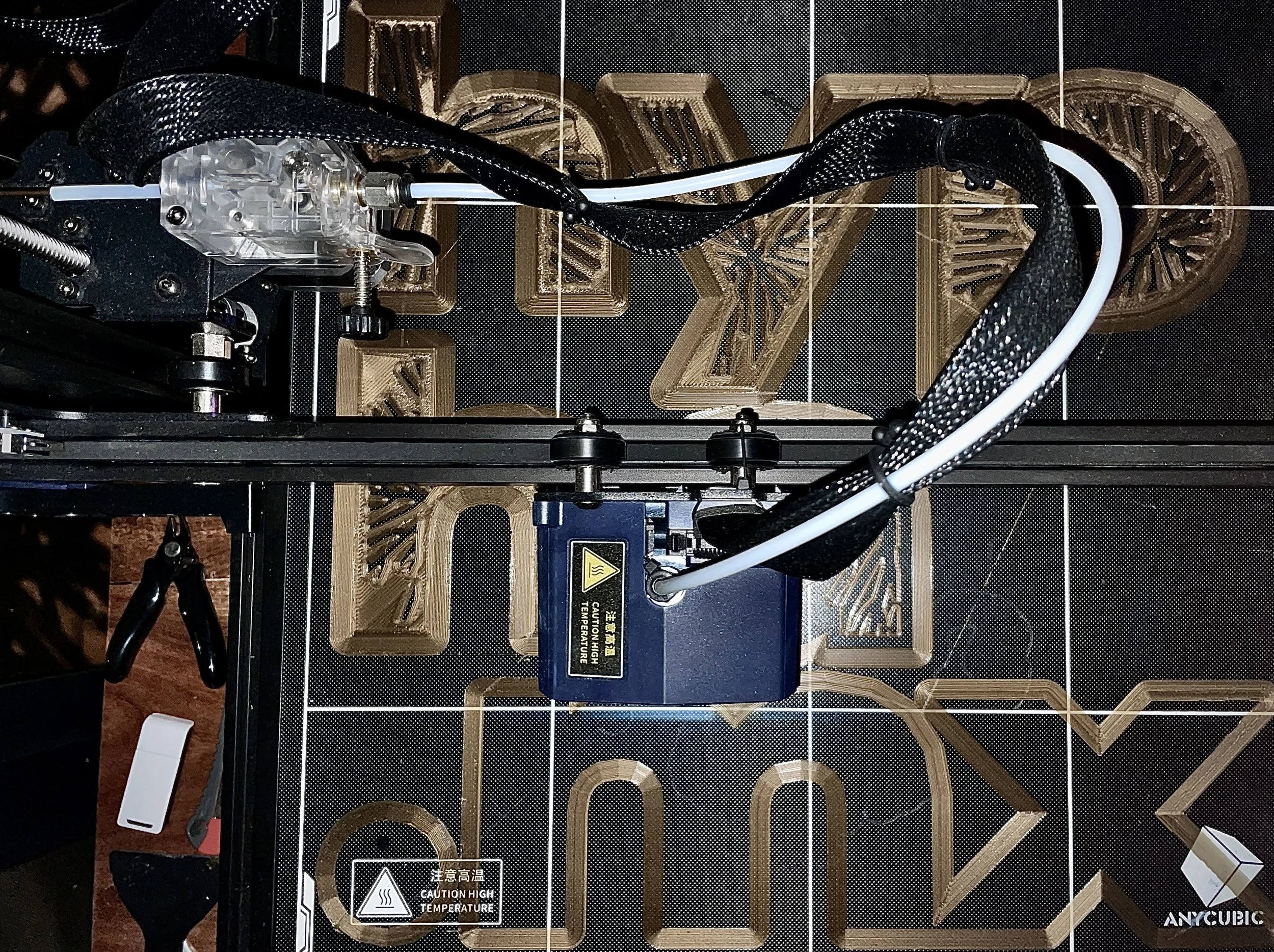 Top-down view of a 3D printer with a partially printed object on the bed and various tools around it. Hypha Inc Marketing Agency and Creative Studio Lab, Tulum.