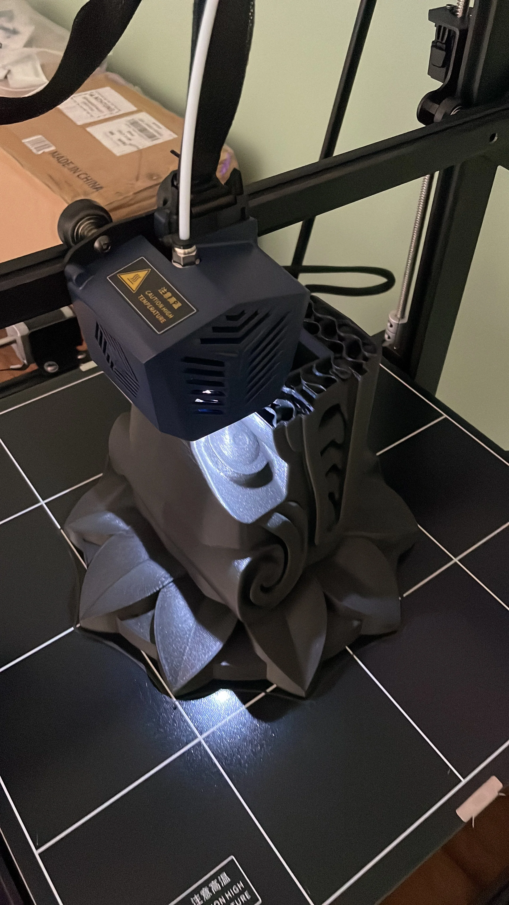 A 3D printer printing an object, with a black and white filament, on a black tiled table. Hypha Inc Marketing Agency and Creative Studio Lab, Tulum.