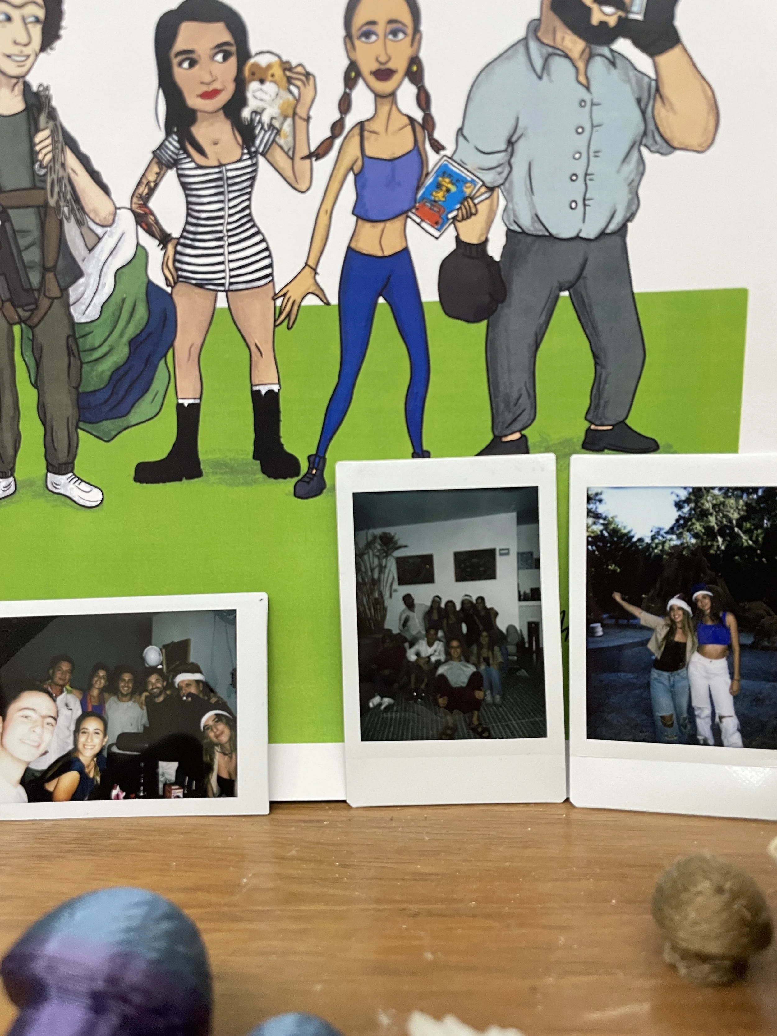 Hypha Inc. Decorative wall with cartoon characters and three polaroid photos of people at a gathering or party.