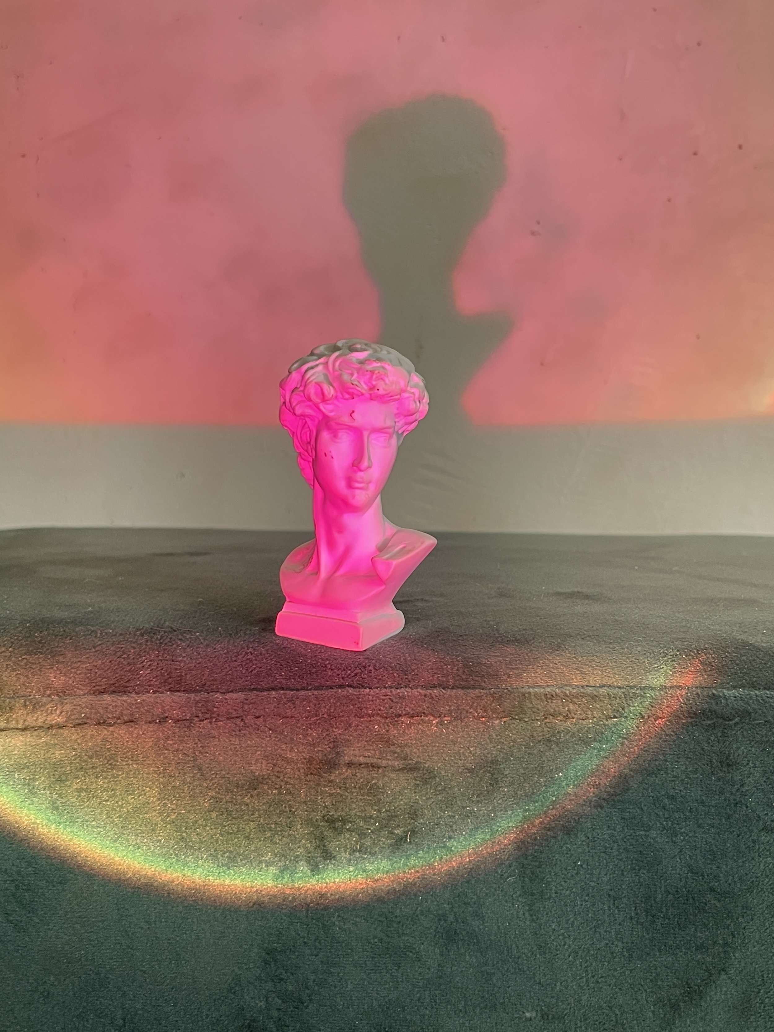 Pink bust of a classical sculpture with rainbow-colored light reflections, silhouette shadow on the pink background. Hypha Inc Marketing Agency and Creative Studio Lab, Tulum.