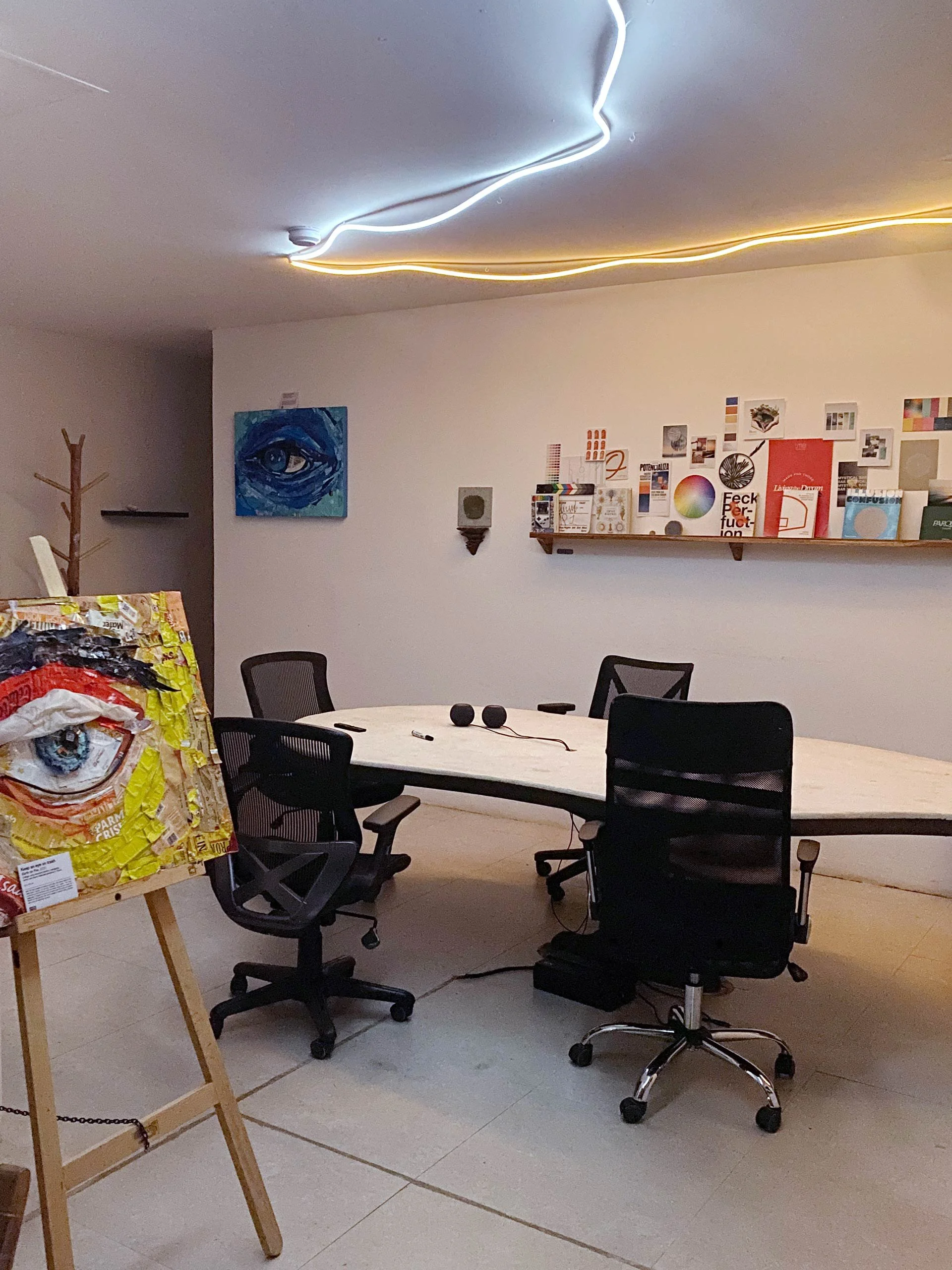 Hypha Inc. Creative Lab and A studio or gallery space with a large white table, black office chairs, and various art supplies and artworks on the walls. Marketing Agency Tulum