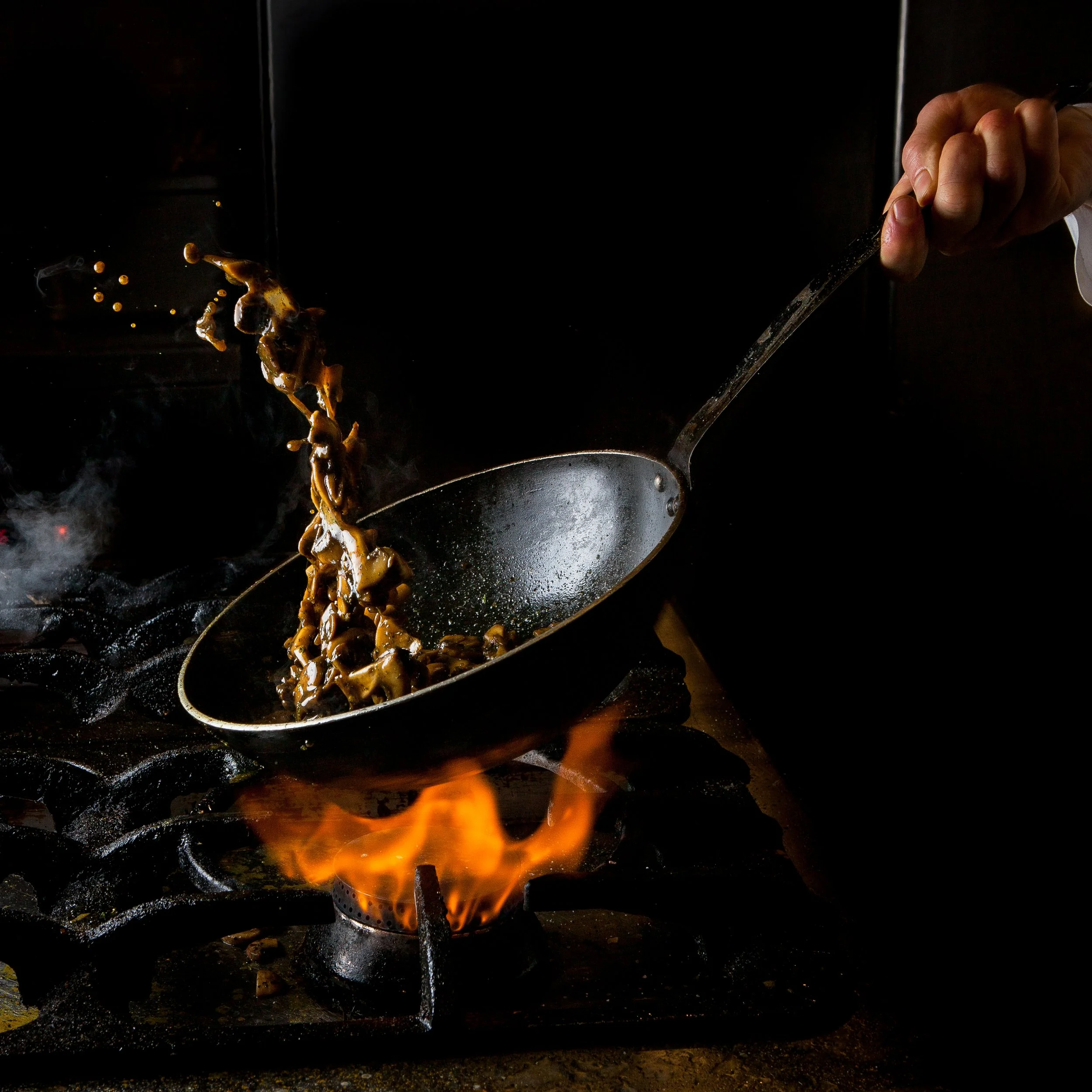 side-view-mushroom-frying-with-gas-stove-fire-human-hand-pan.jpg
