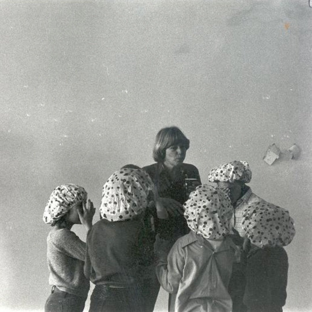 Woman taking a selfie in a mirror with four children, all wearing matching polka dot headscarves.