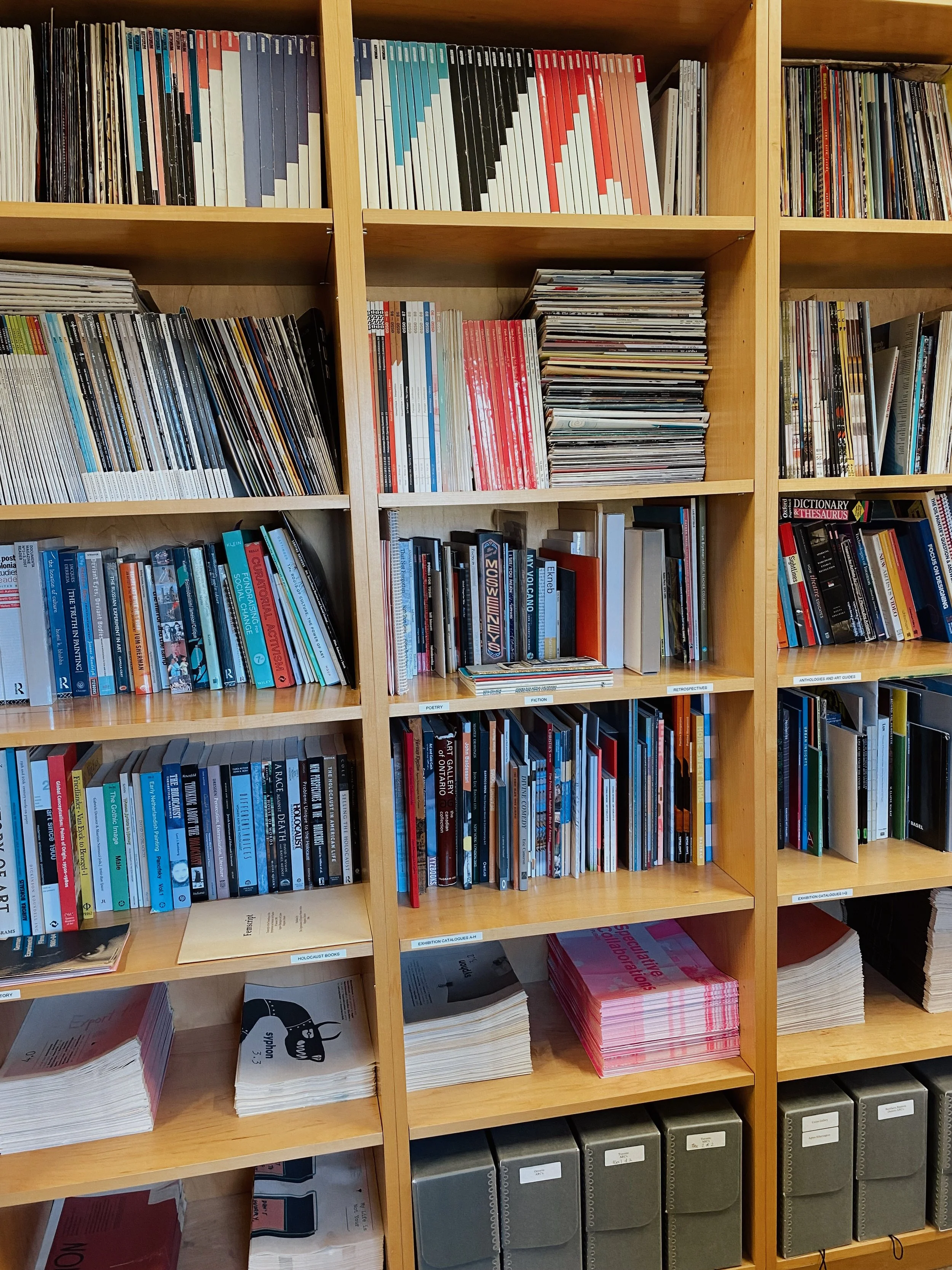 3 Wooden bookshelfs crowded with books and publications.