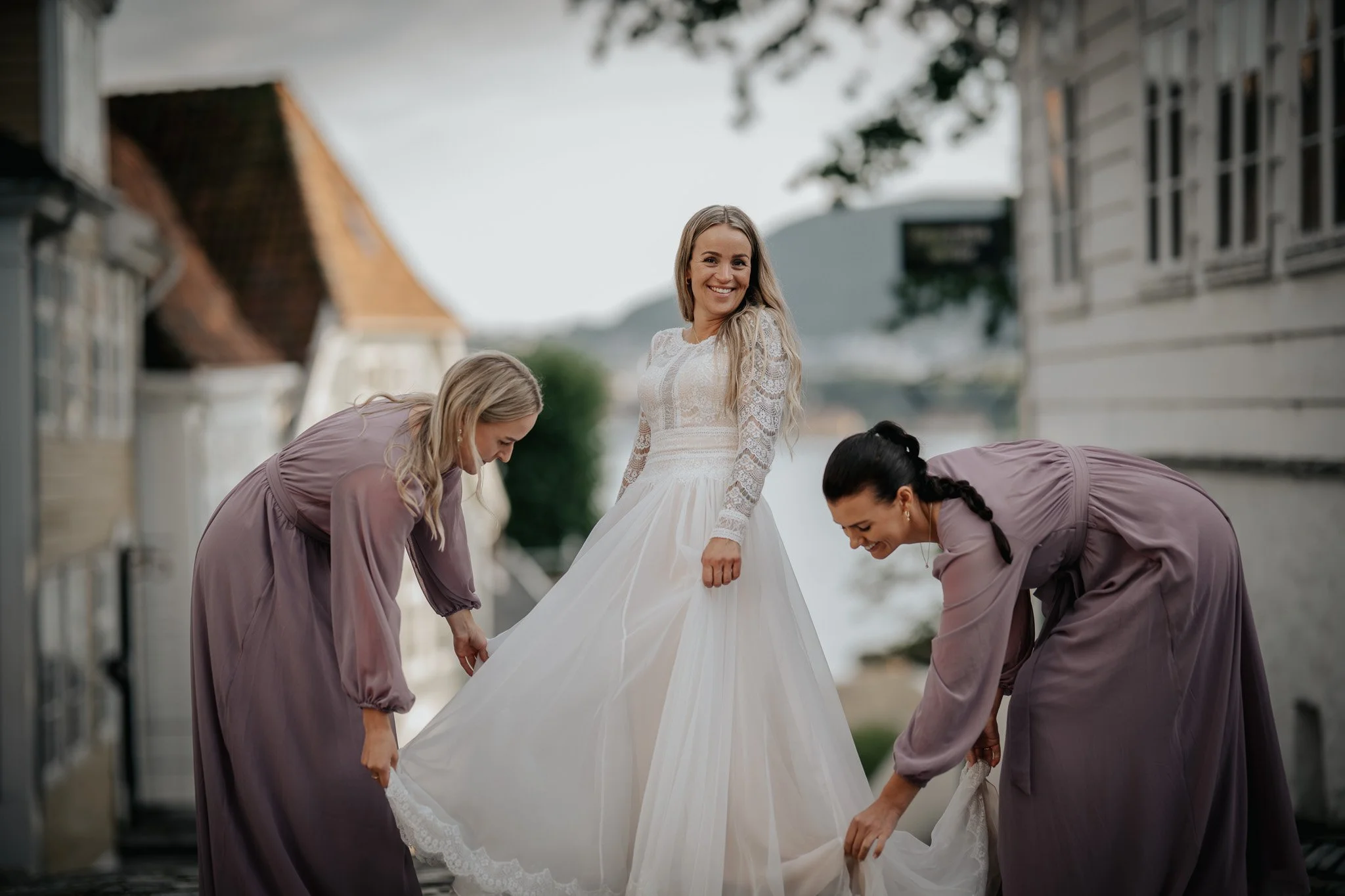 Bryllupsfoto/video: Brud med brudepiker som hjelper med kjolen utendørs.