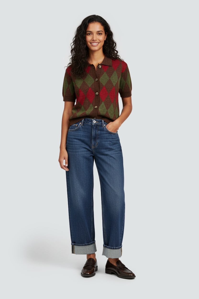 Image IA mode d'Une femme souriante avec des cheveux bouclés longs, portant un polo à manches courtes à motif argyle rouge, vert et marron, avec un pantalon en jean bleu et des chaussures en cuir marron.