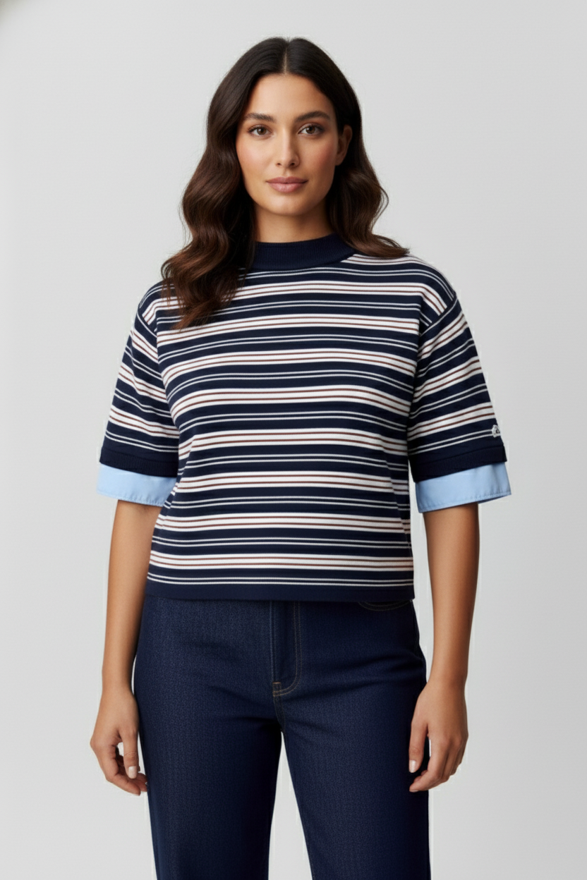 Visuel IA d'une jeune femme aux cheveux bruns, portant un pull à rayures bleu marine et blanc, avec des manches retroussées, et un pantalon bleu foncé.