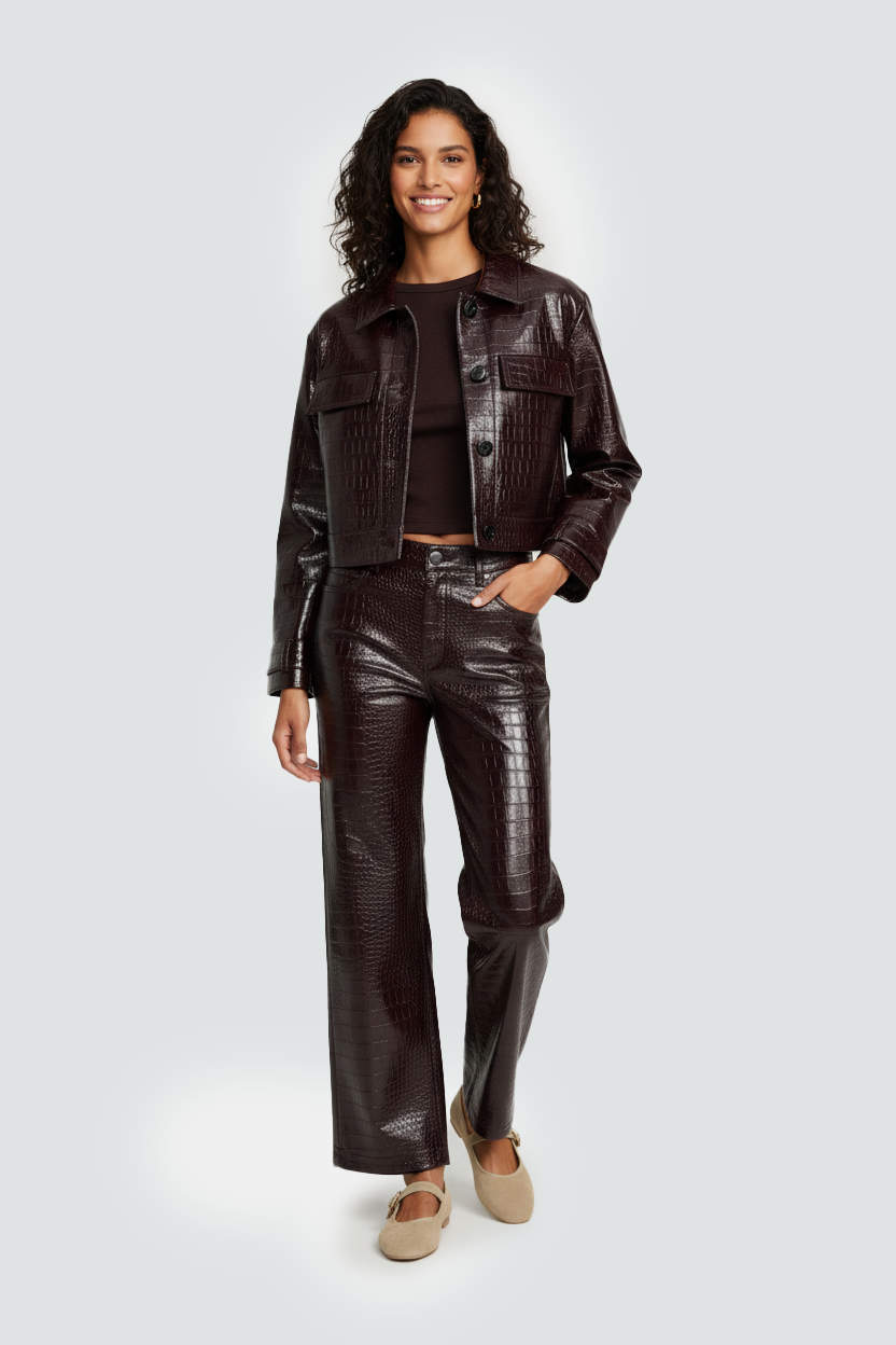 Image IA mode d'Une femme souriante portant une veste marron en imitation crocodile, un haut noir, un pantalon assorti en imitation crocodile, et des chaussures beige.