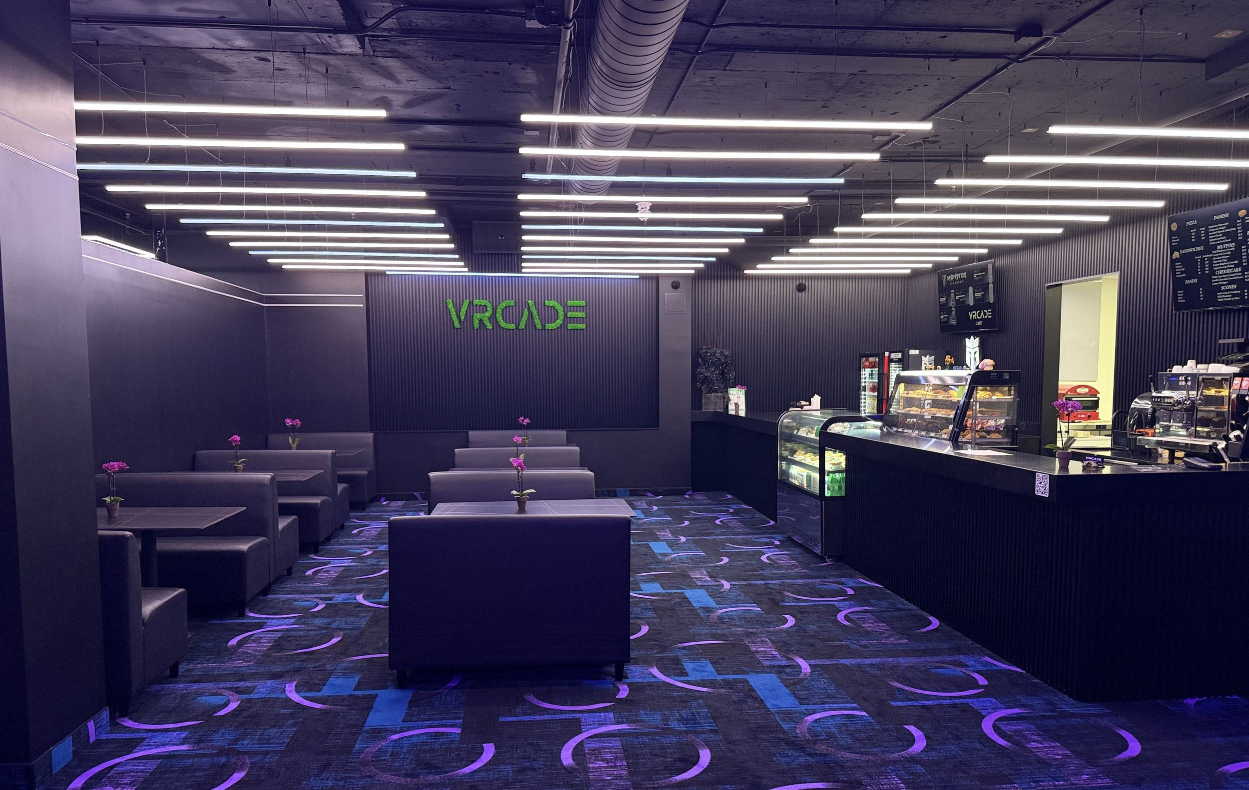 Inside a modern arcade with black and purple decor, neon green