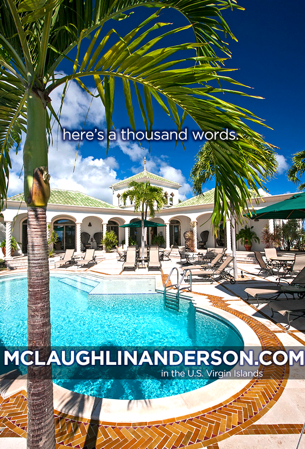 Luxury resort pool area with palm trees, lounge chairs, umbrellas, and historic-style white building under a blue sky with clouds, in the U.S. Virgin Islands.