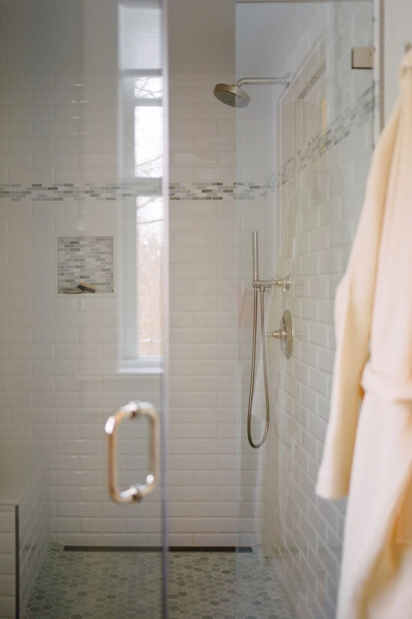A clean, minimal walk-in shower with white subway tile and a linear drain