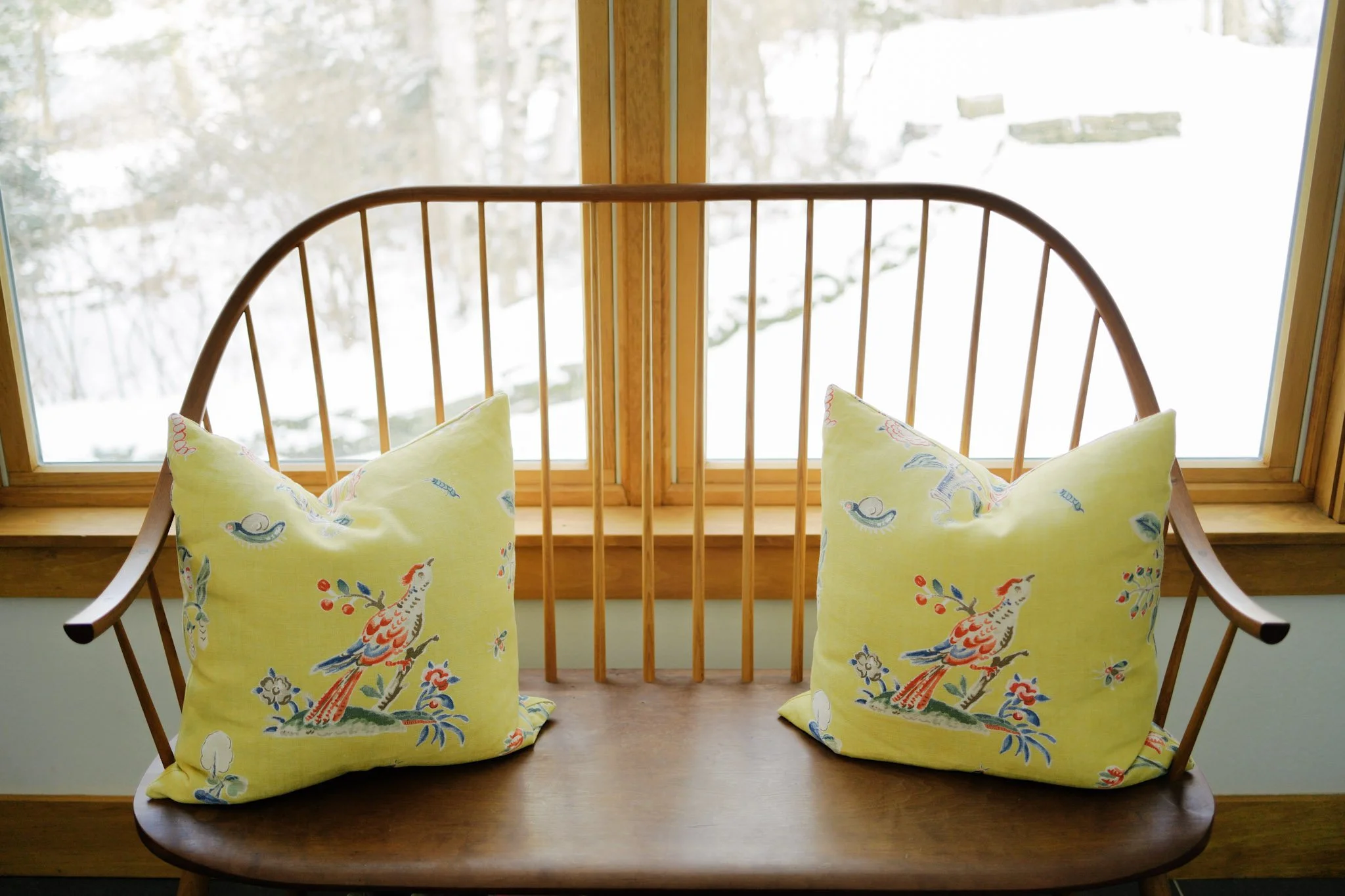 A window seat with blue and white patterned pillows overlooking a snowy winter landscape