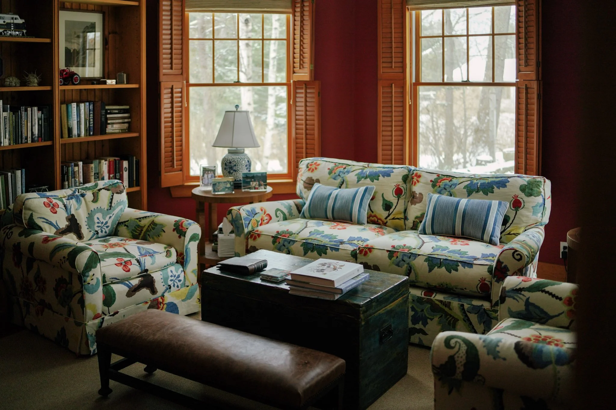 Cozy living room with custom floral sofas and wooden shutters designed by Brookfield Hunt Studio, Portland, Maine interior designers.
