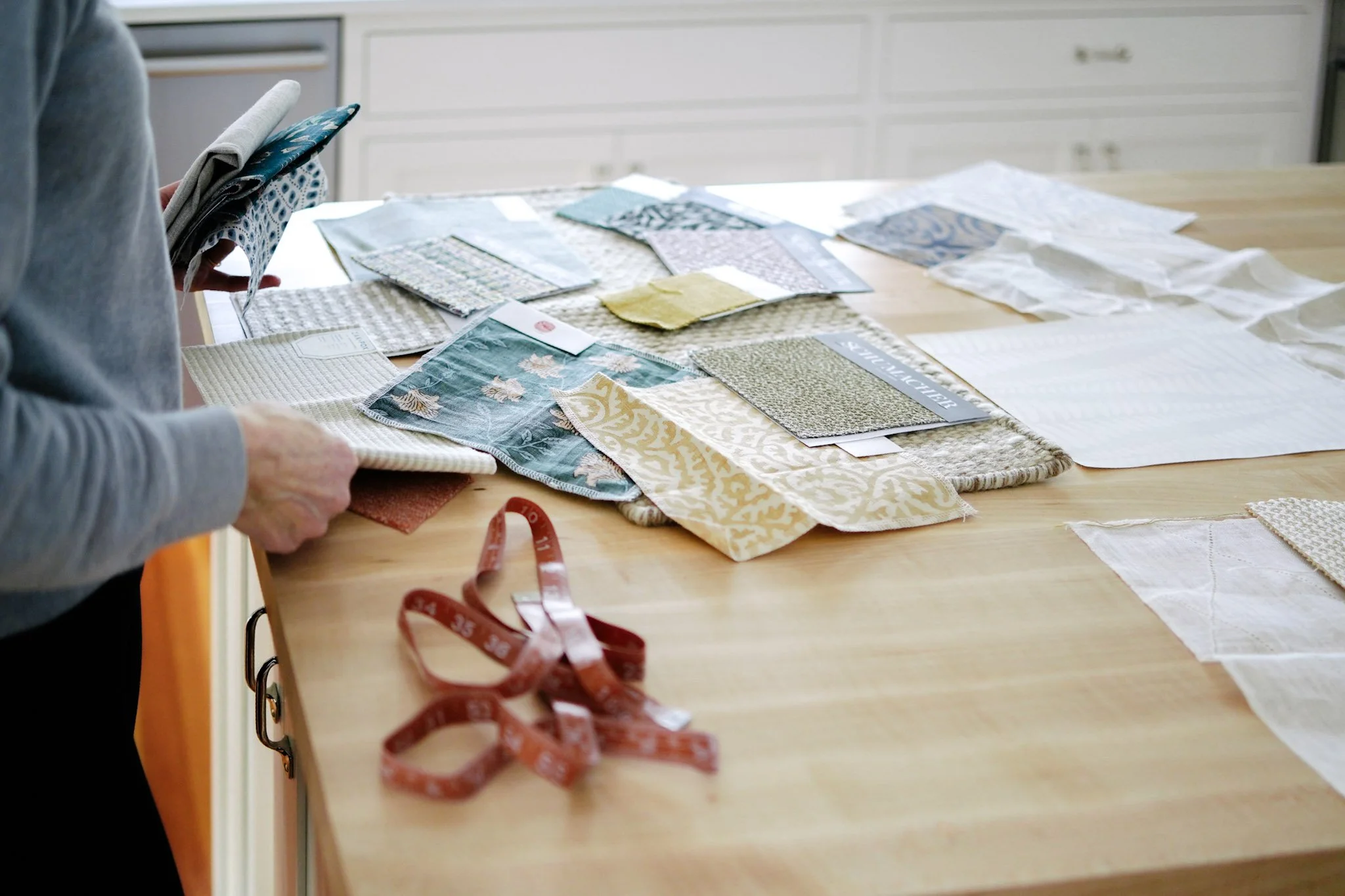 Interior designer selecting fabric swatches for a custom home design project in Portland, Maine.