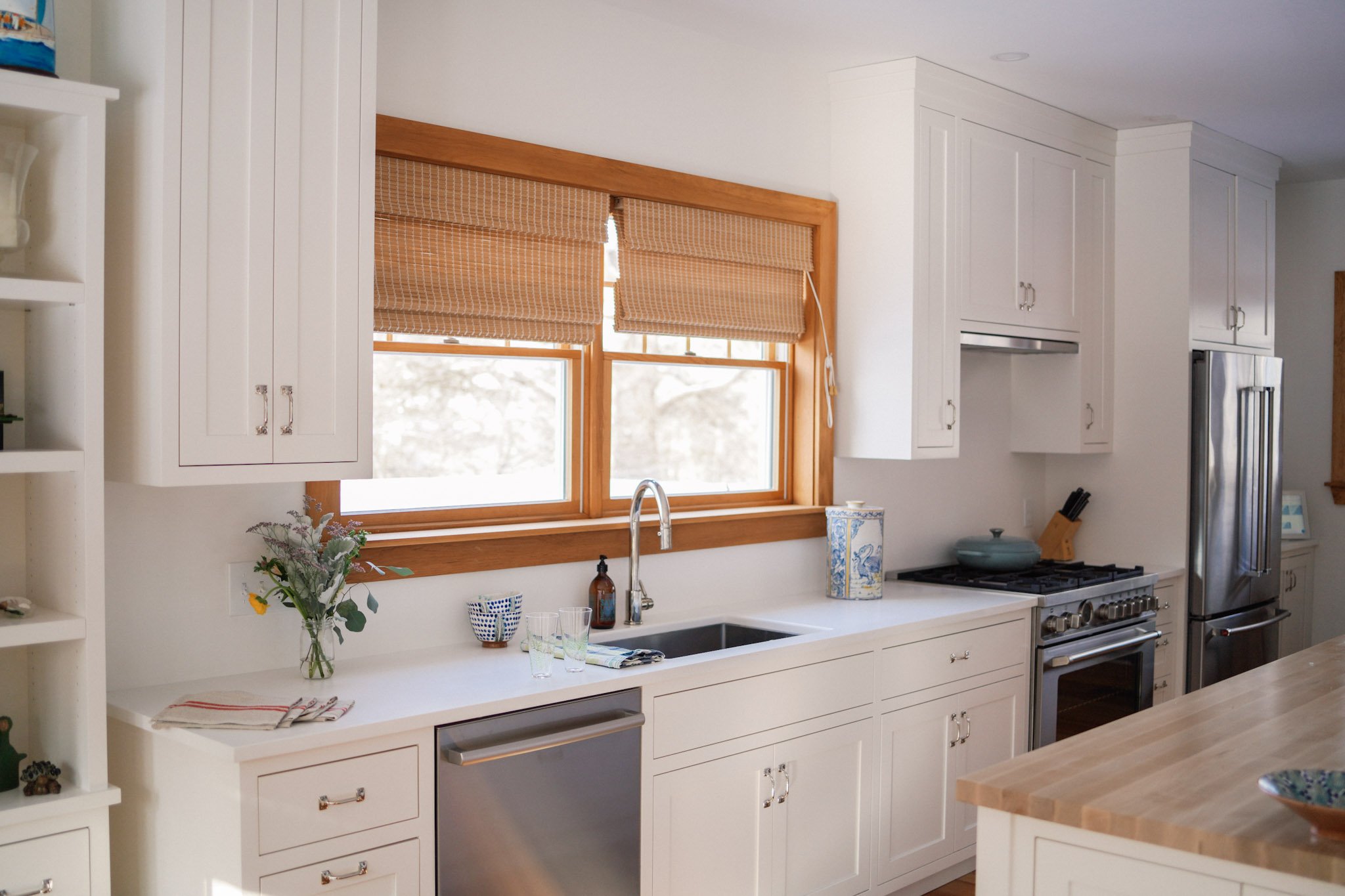 A bright, airy white kitchen with wood-trimmed windows and classic finishes