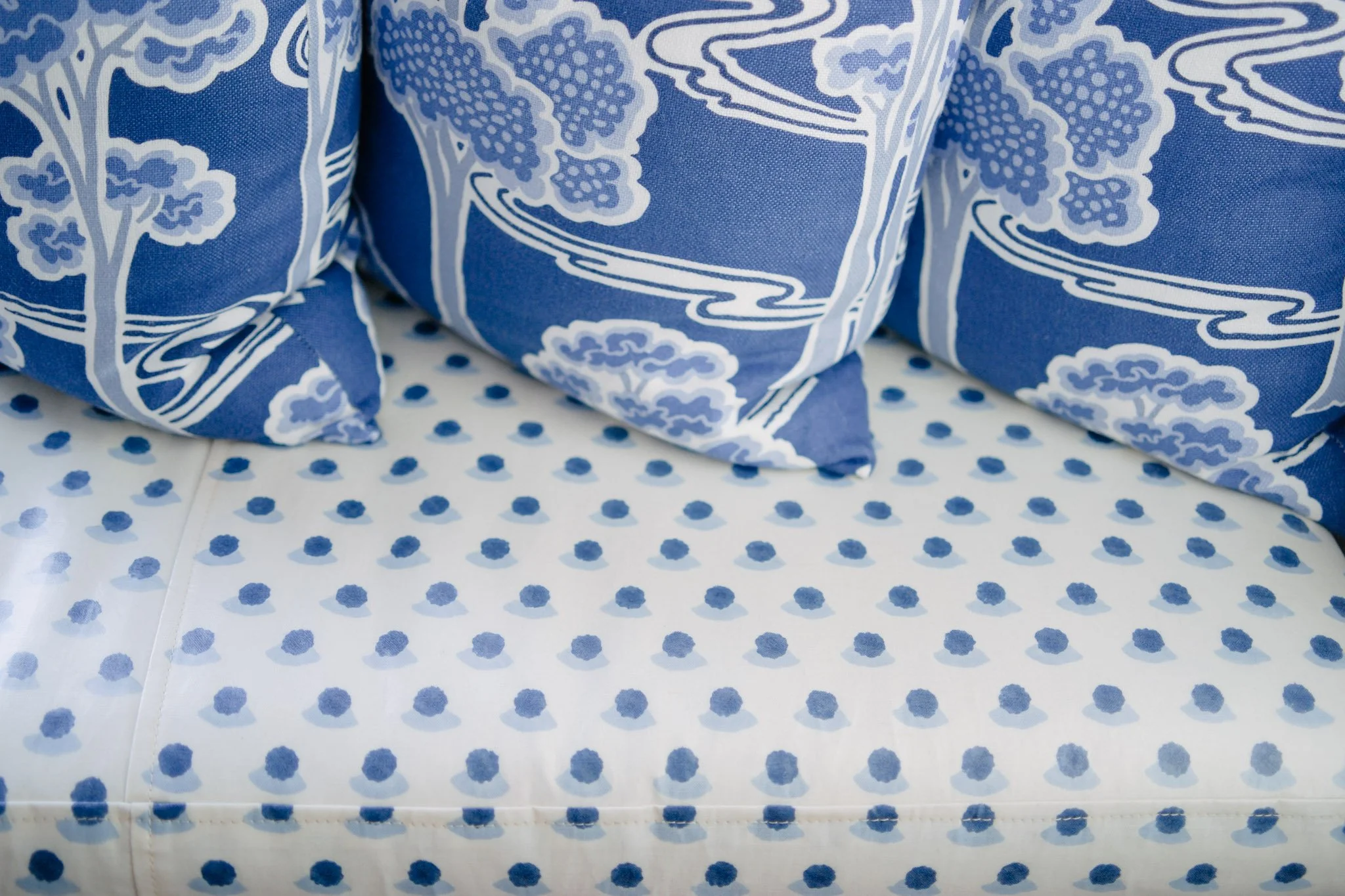 Blue and white printed fabric with a tree and cloud pattern, resting on a polka dot surface