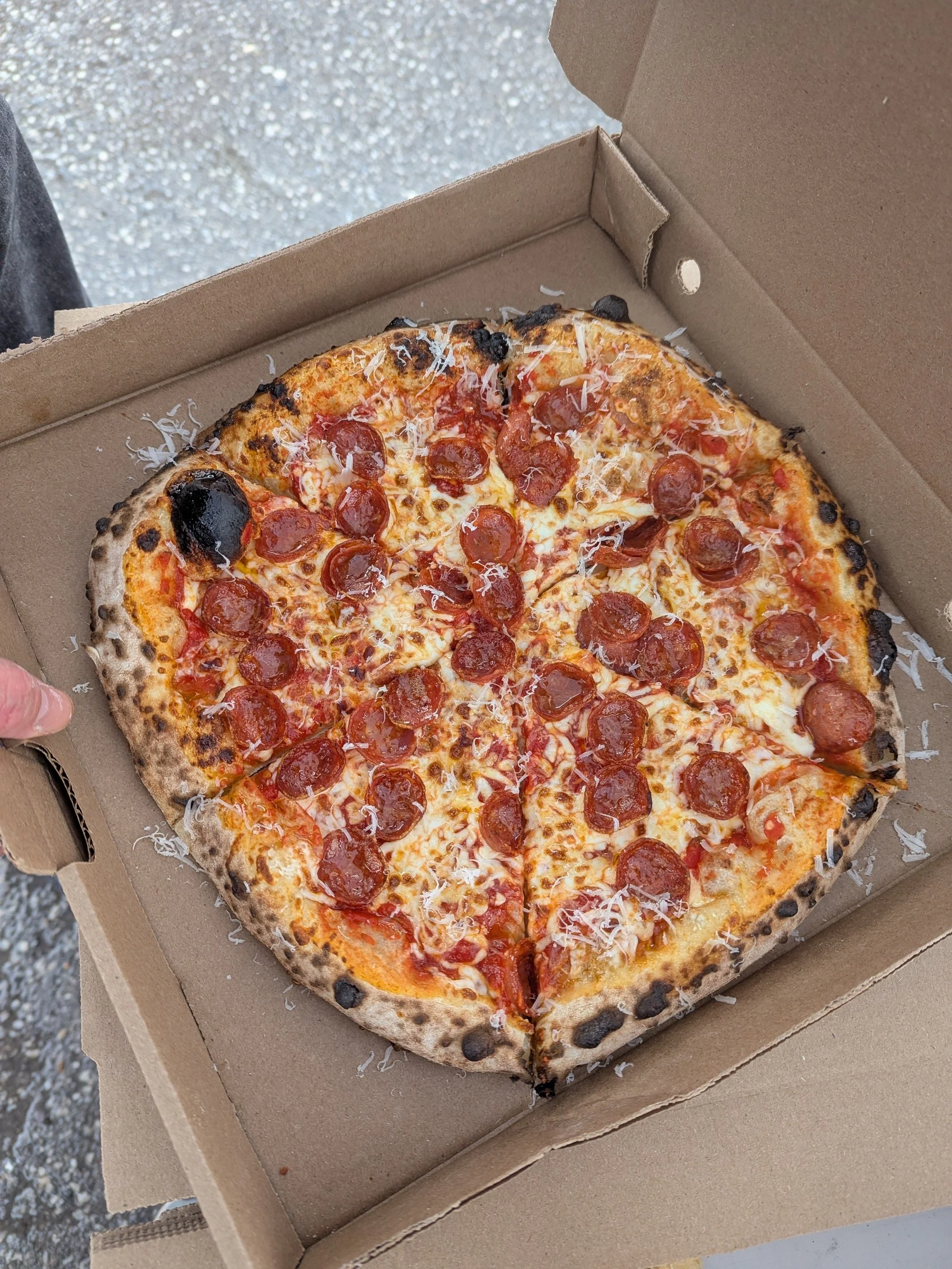 A pepperoni pizza with cheese in a cardboard takeout box.