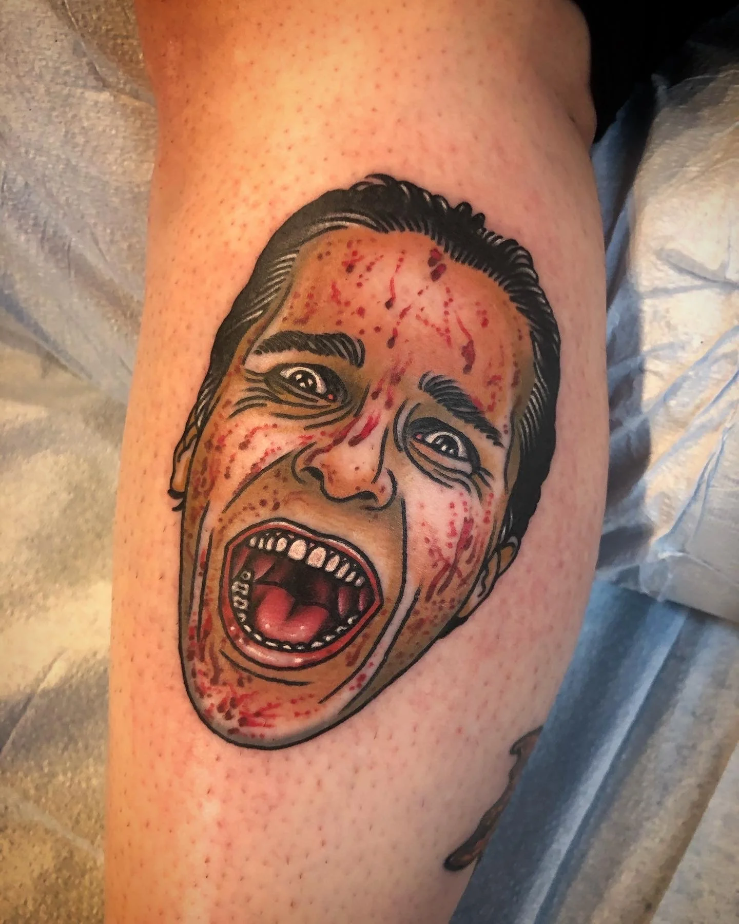 Tattoo of a screaming person's face with detailed shading and red ink, resembling a comic or graphic style.