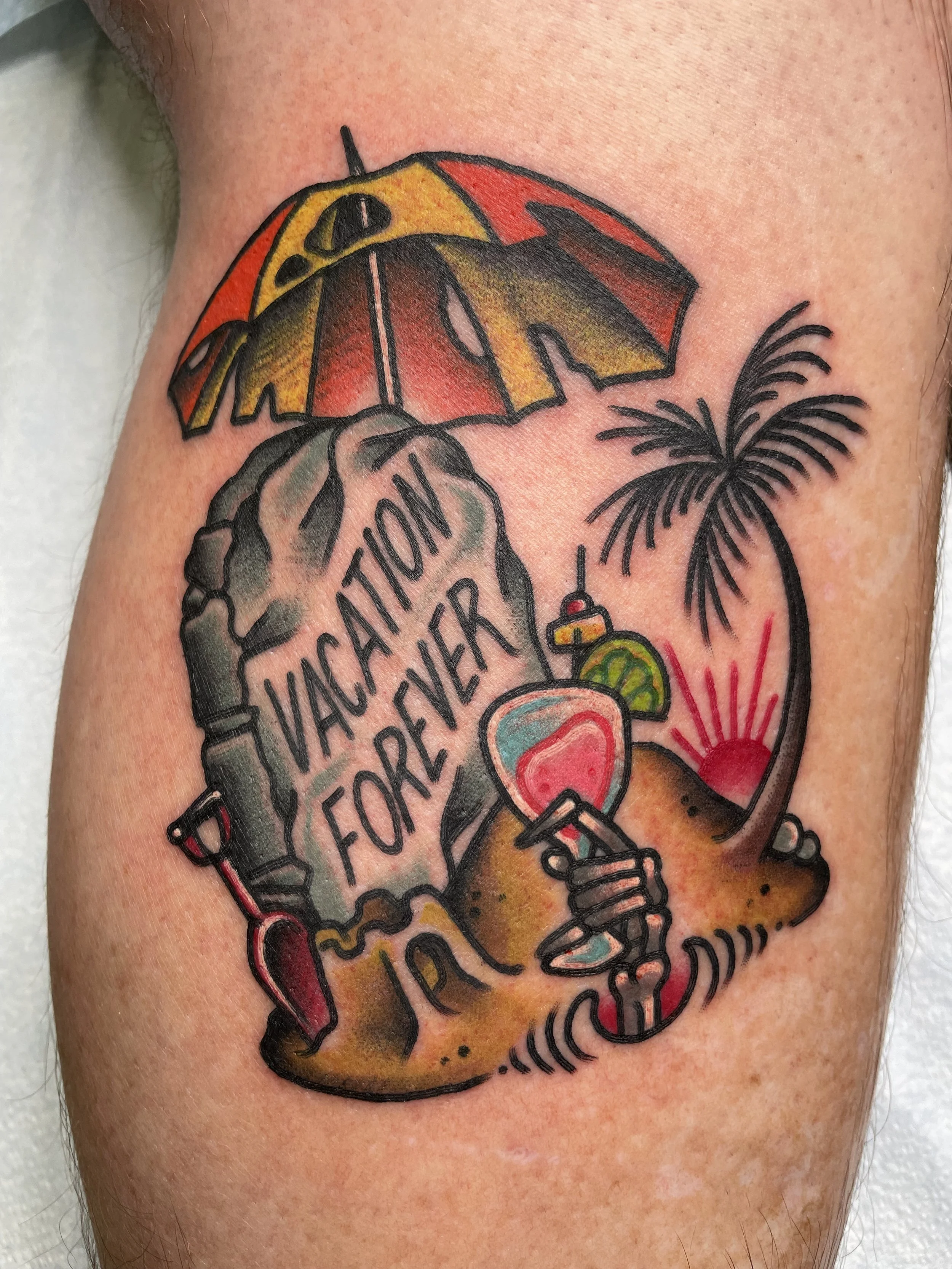 A colorful tattoo featuring a beach scene with a yellow and red umbrella, a palm tree, a sunset, a large tattooed arm holding a drink with a lime and a heart, and a rock with the words 'VACATION FOREVER' in black ink.