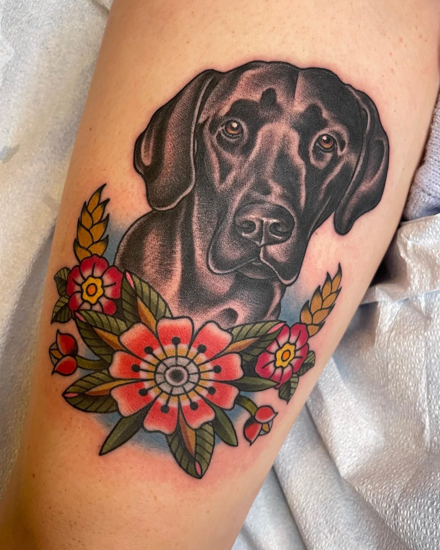 Tattoo of a black and brown dog with floral design surrounding its neck.