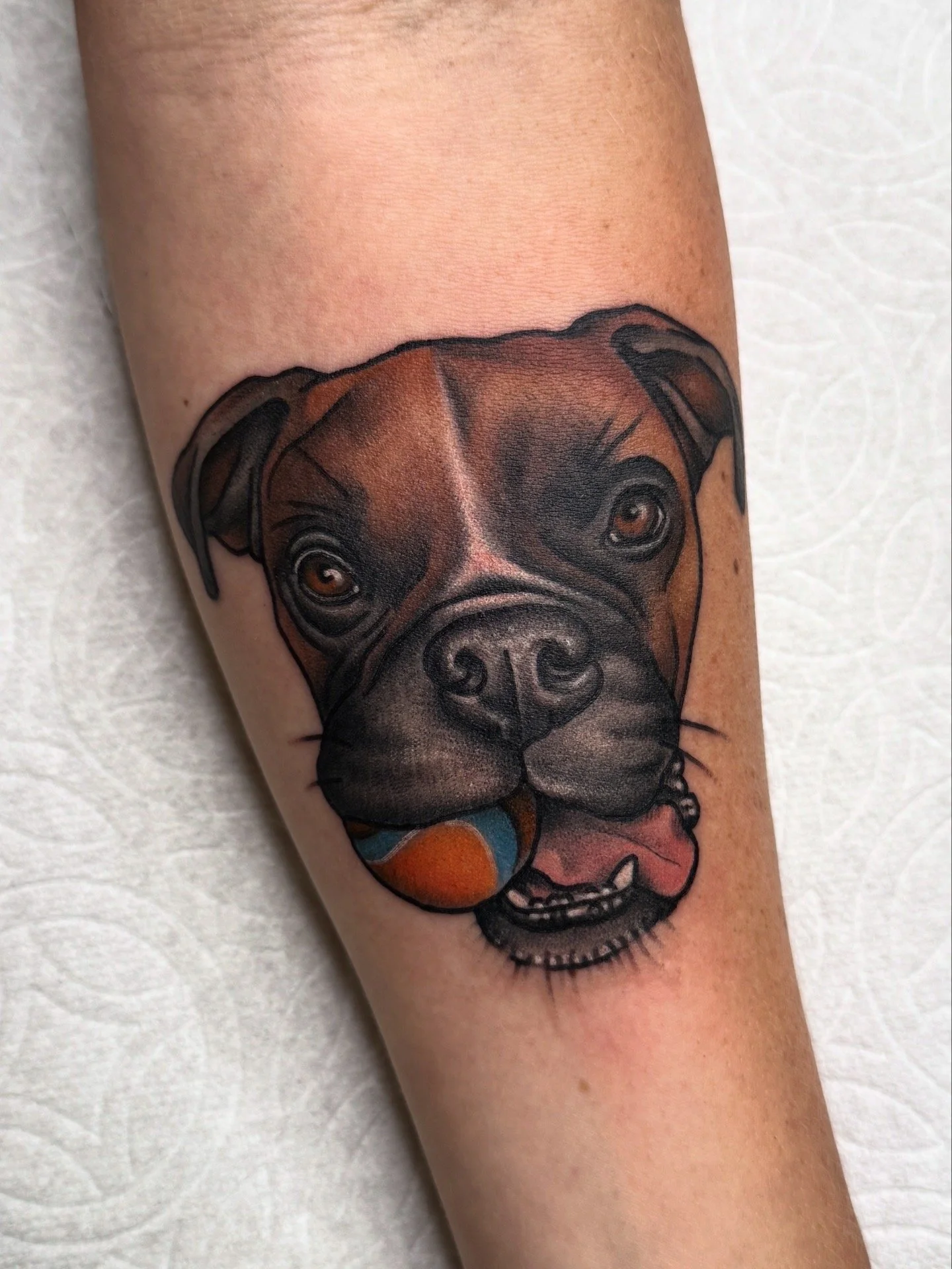 Colorful tattoo of a dog's face on a person's arm.